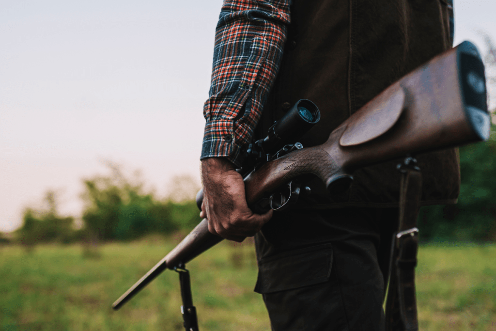 Real hunter in the field holding rifle and binoculars