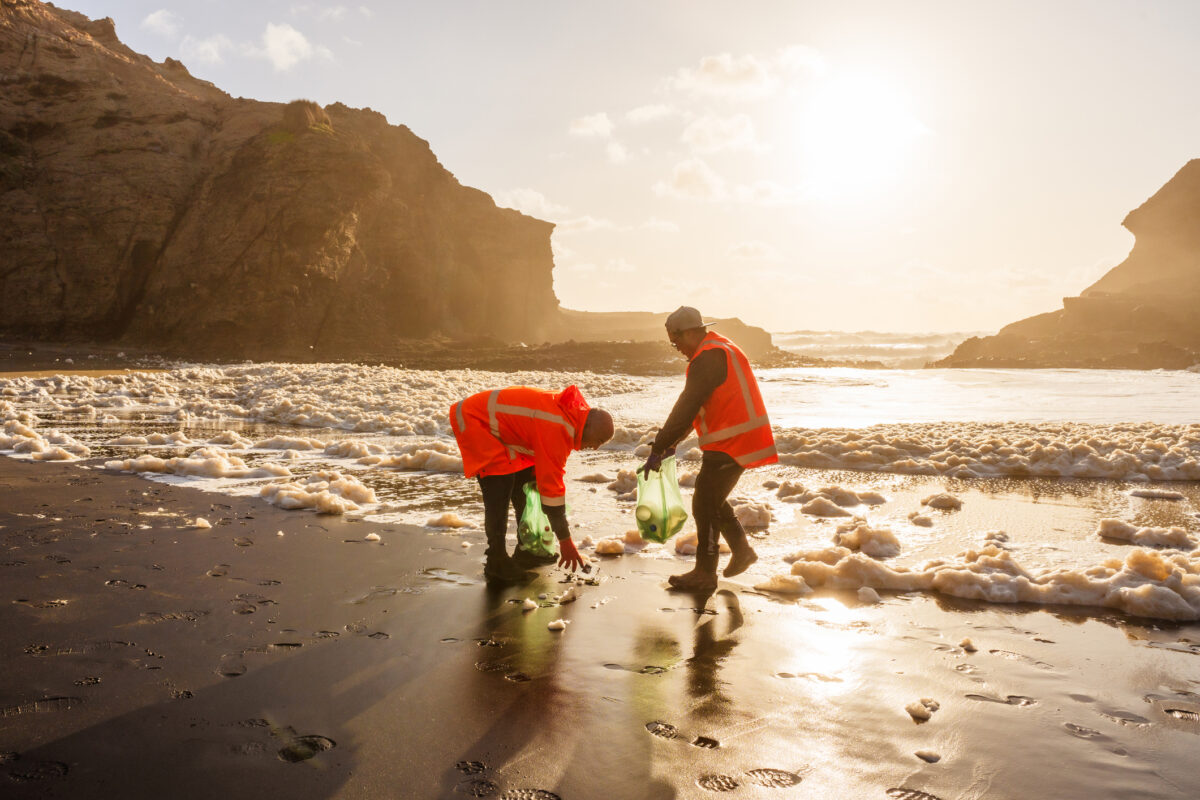 volunteers picking up trash on the beach for ocean water conservation