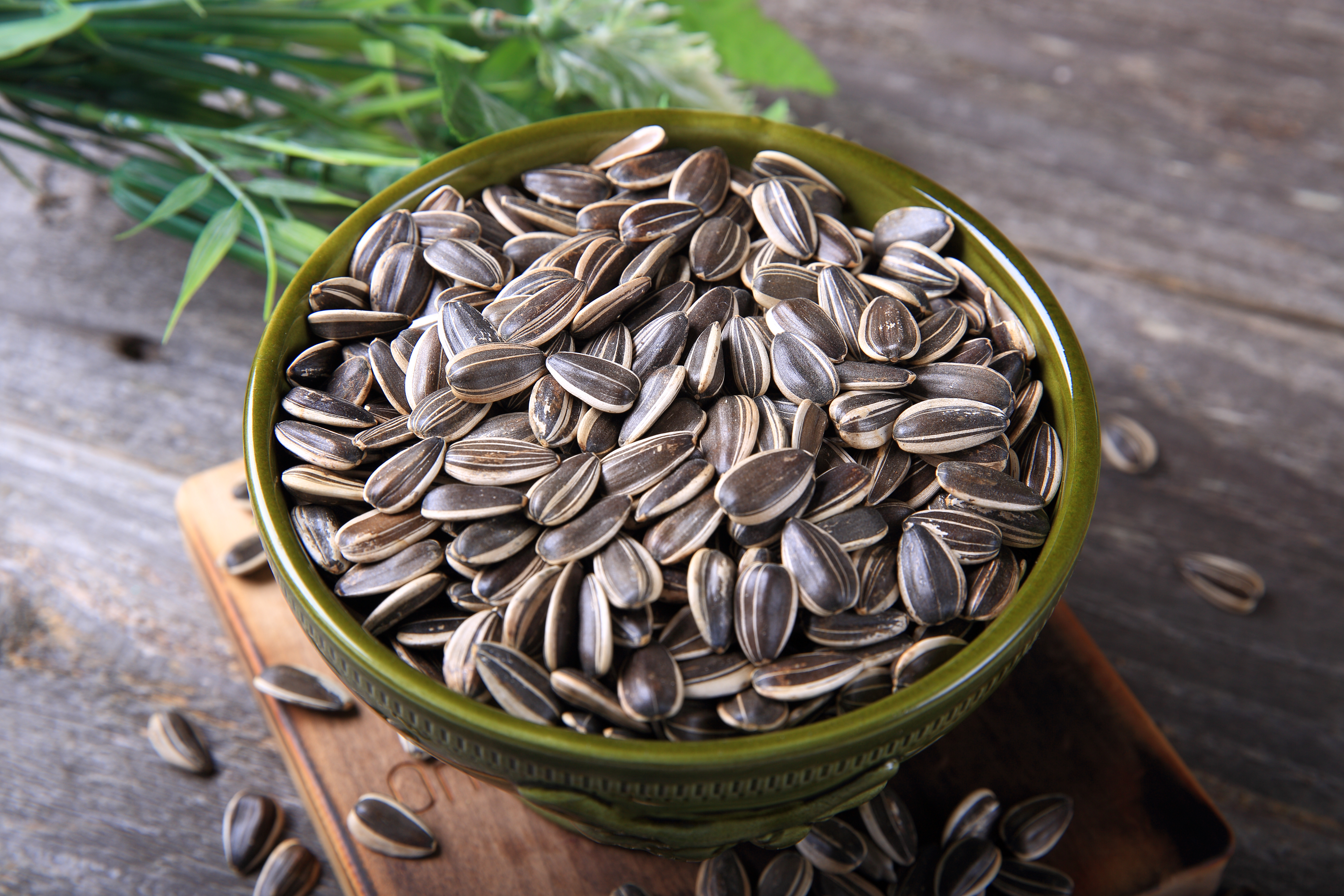 Sunflower seeds in a bowl on a wooden table.