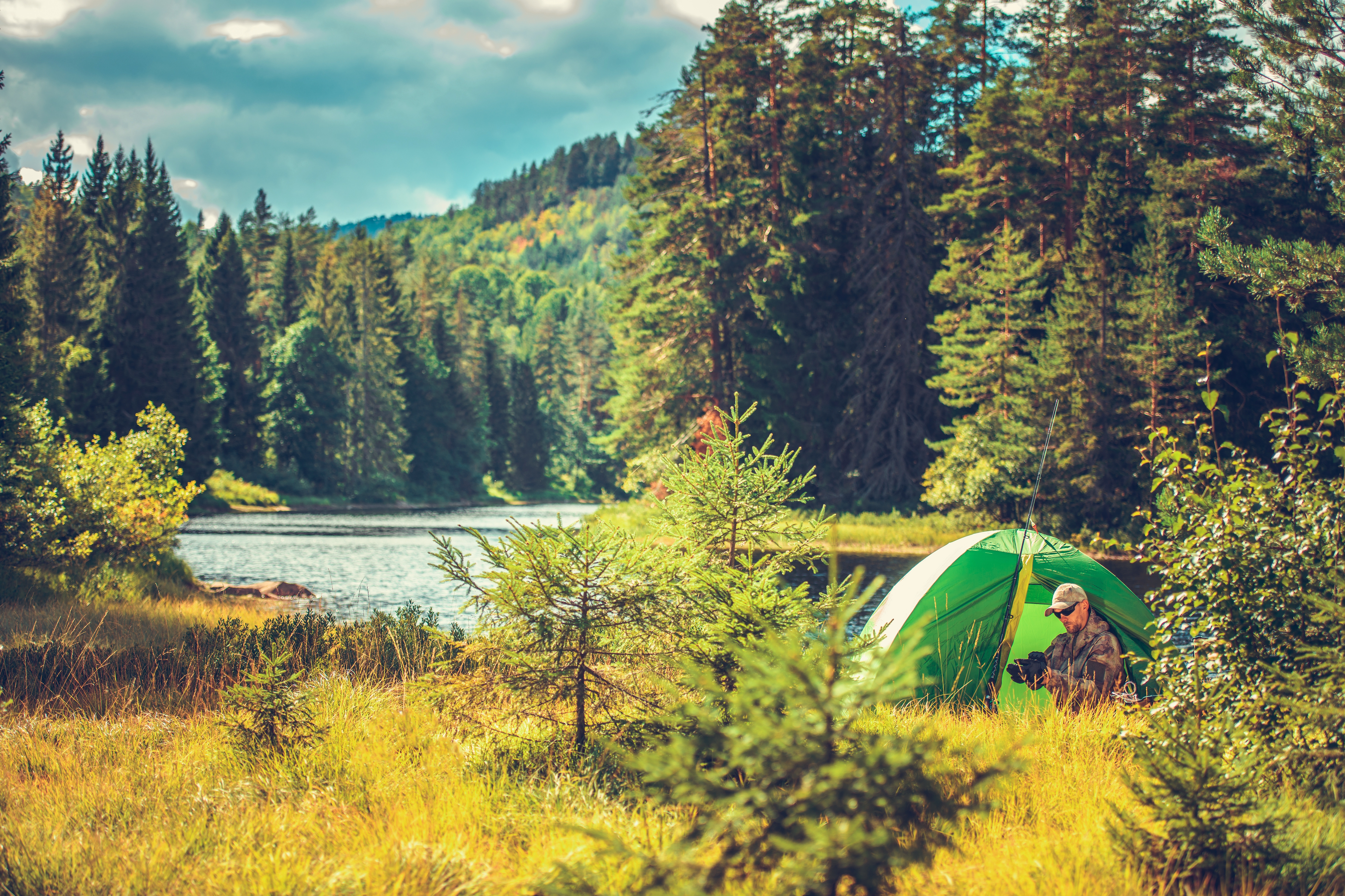 Survival Camping in the Wild. Caucasian Men in His 30s in a Tent Preparing His Equipment For the Fly Fishing