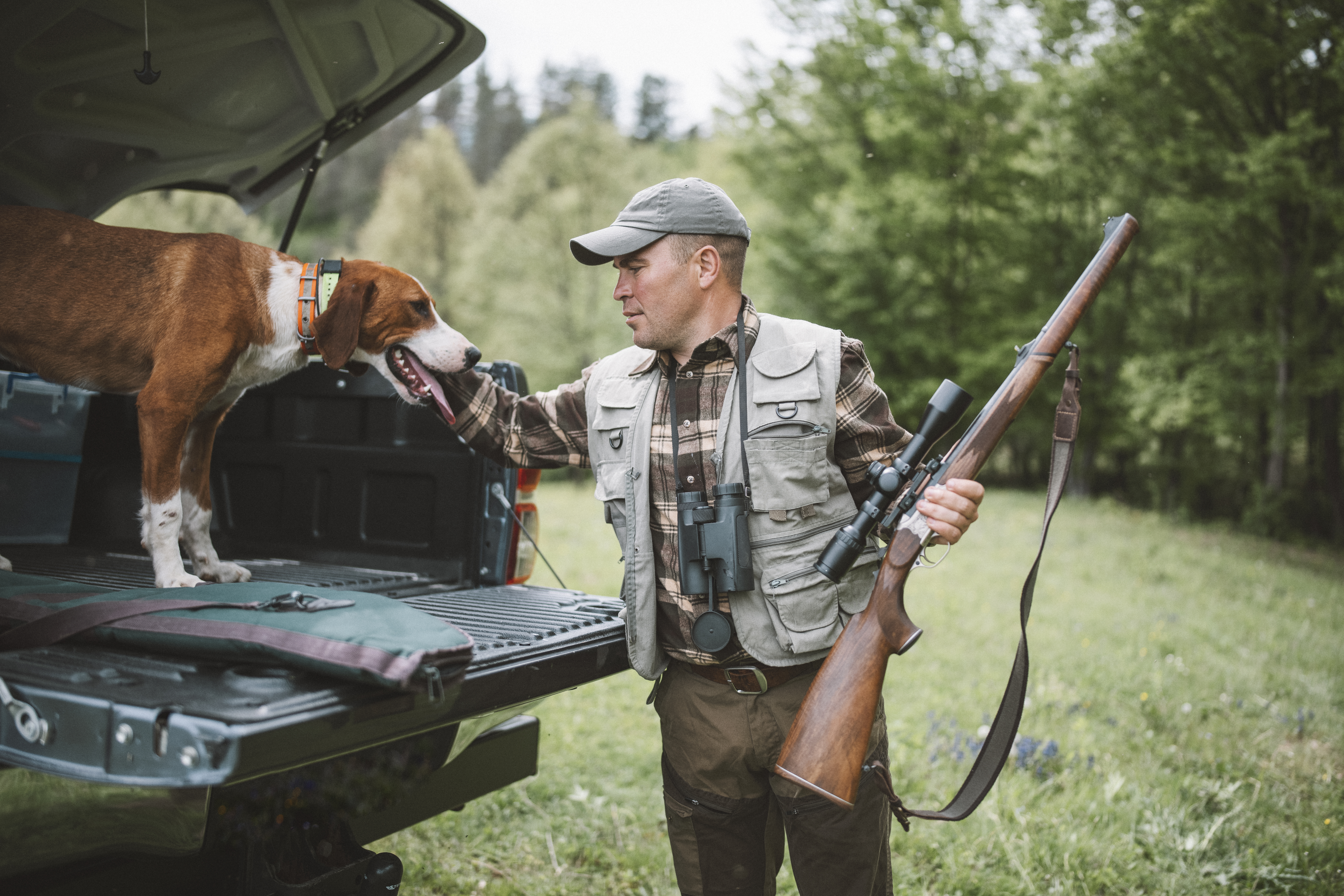 A shot of a hunter with riffle and his dog preparing for a hunt.