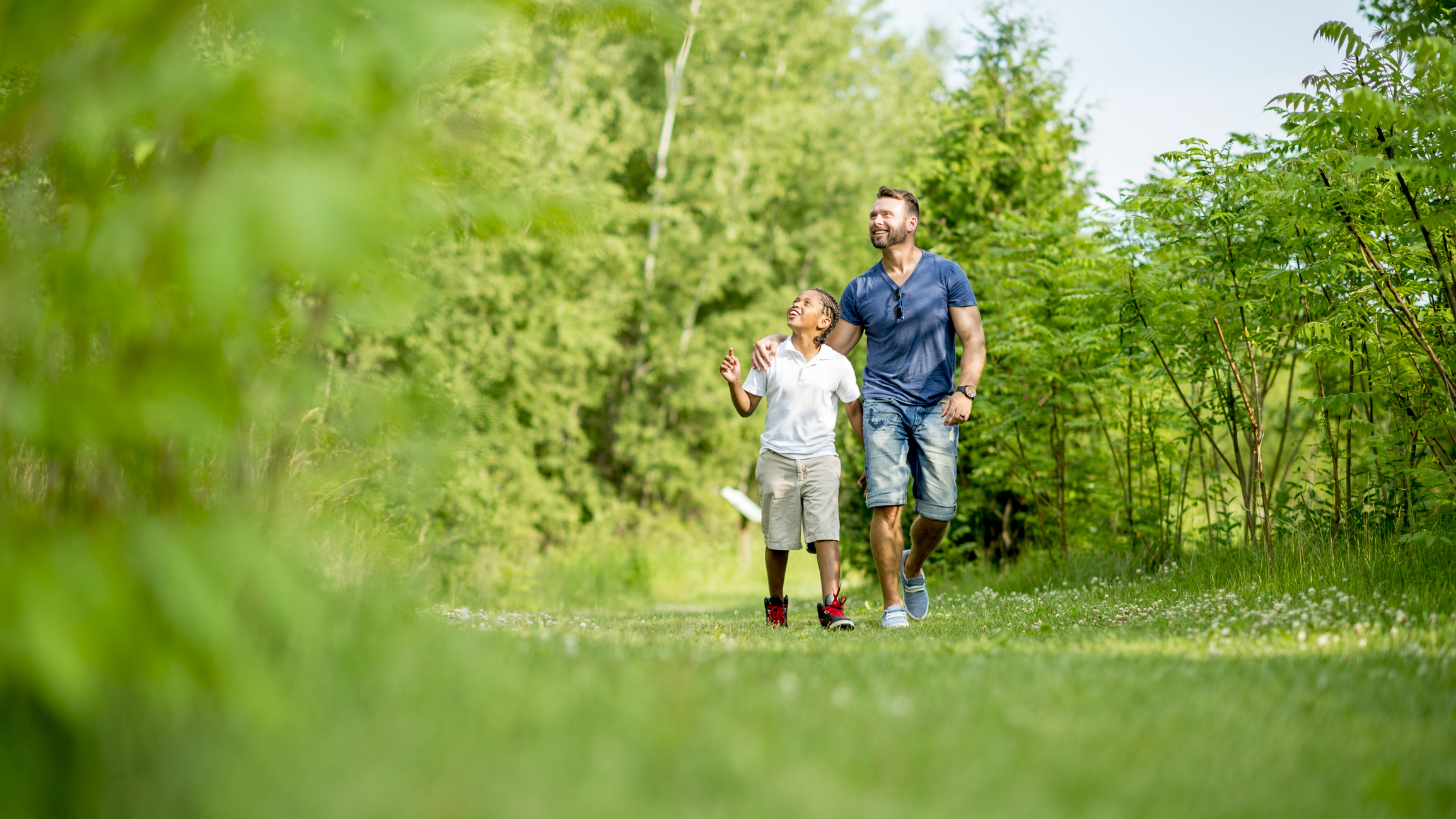 A multi-ethnic family, father and son, going for a walk through nature in a park.