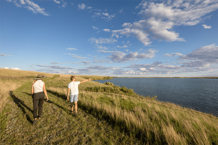 a couple points at the sky next to a huge lake