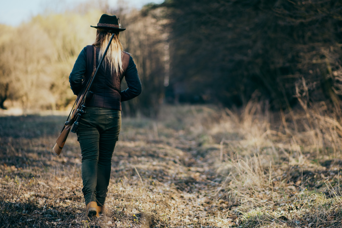 Young woman hunting, walking away from camera