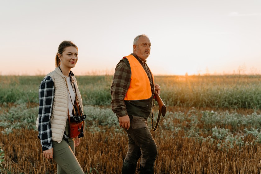 man and woman hunting in field.