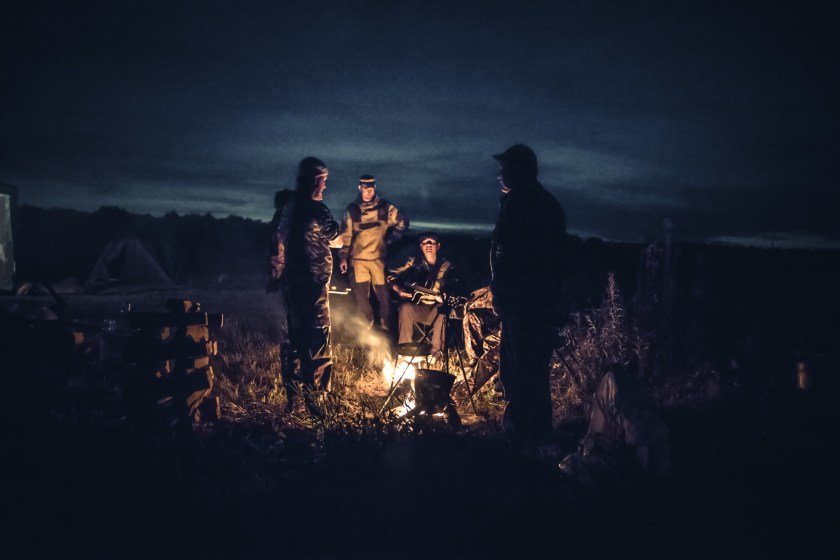 Group of men people travelers tourist resting campfire in outdoors camp after long hunting day in the night