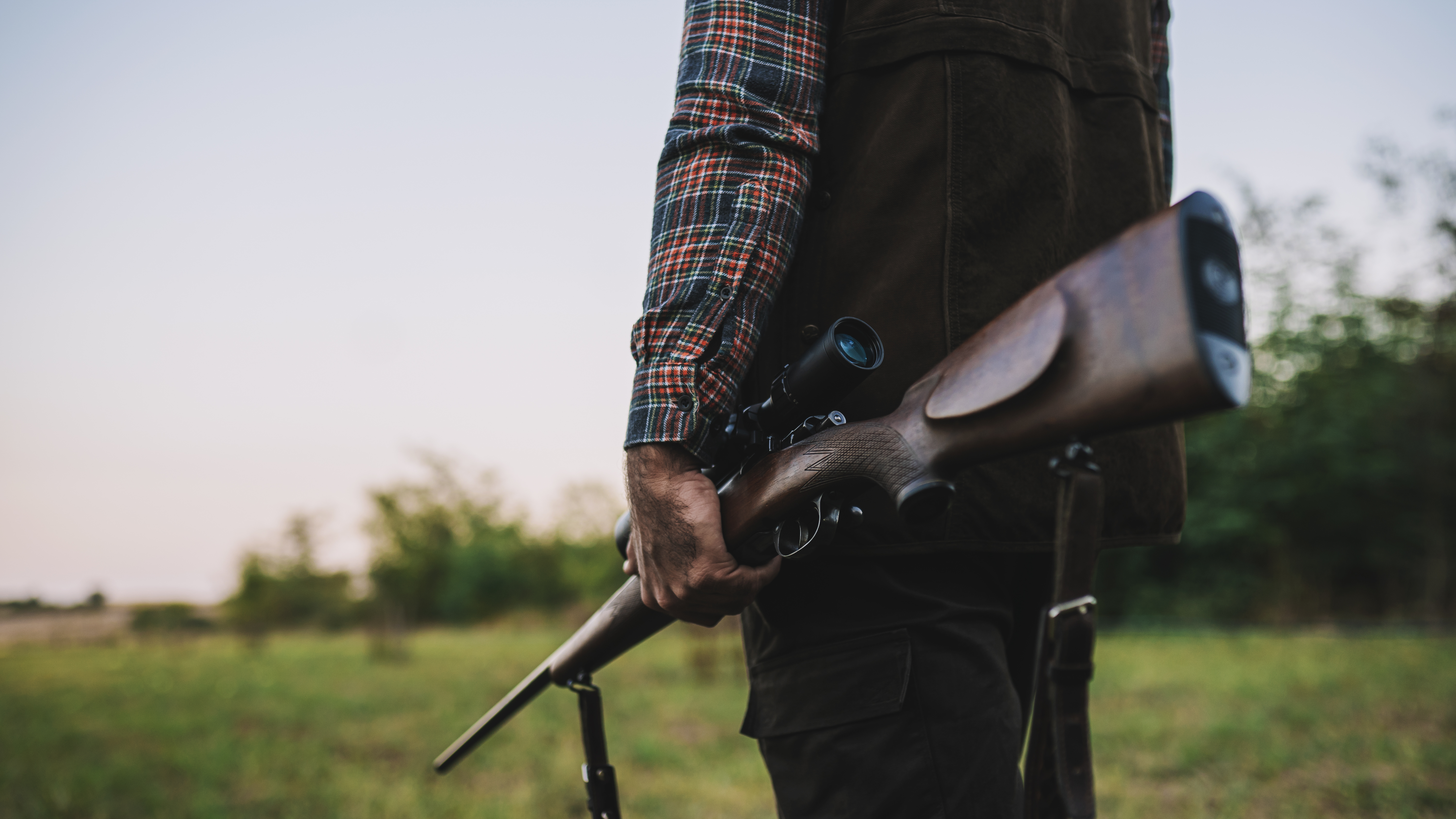 Real hunter in the field holding rifle and binoculars