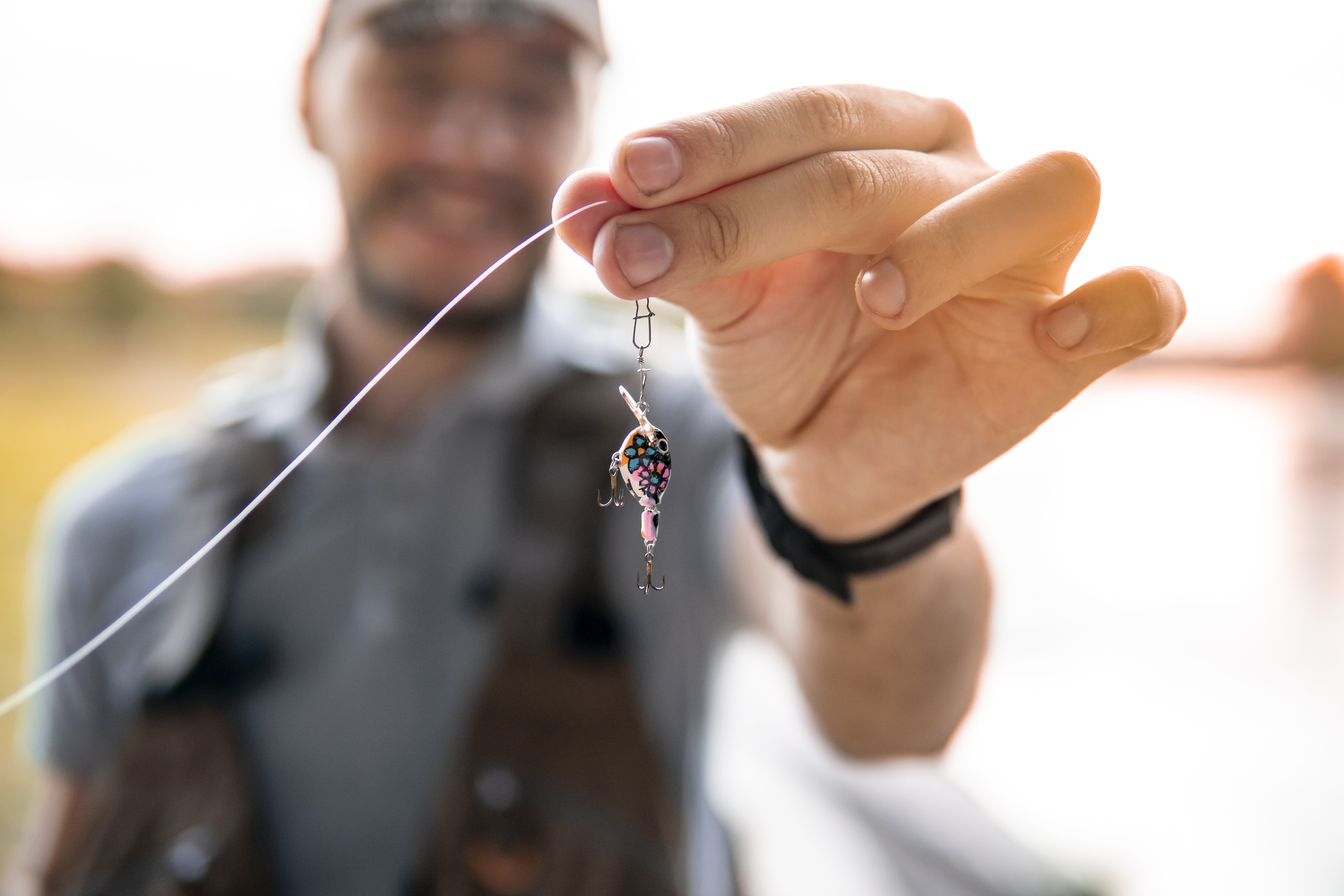 Picture of a caucasian guy, a fisherman showing a fishing lure