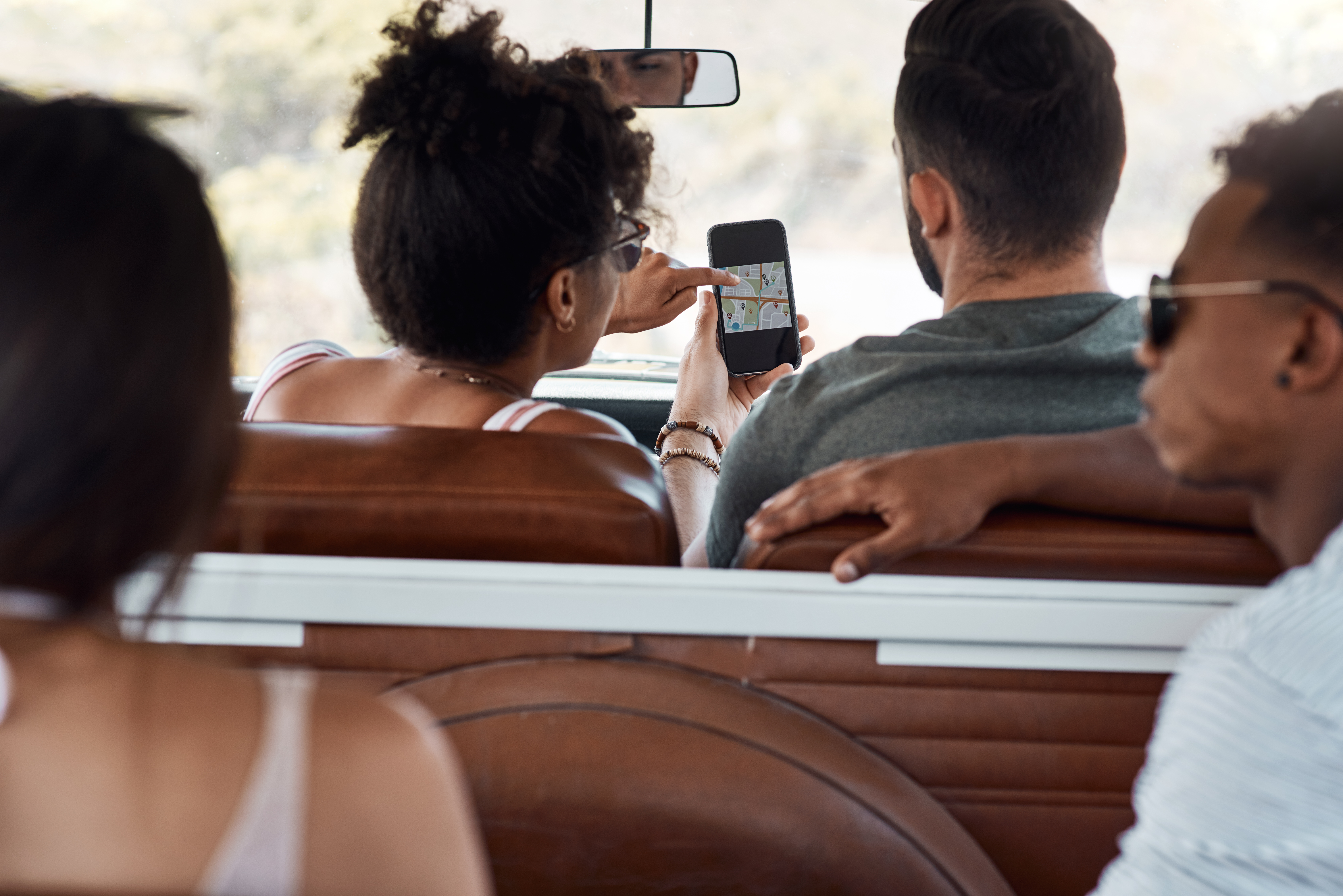Shot of a group of young friends using gps on a smartphone during a road trip