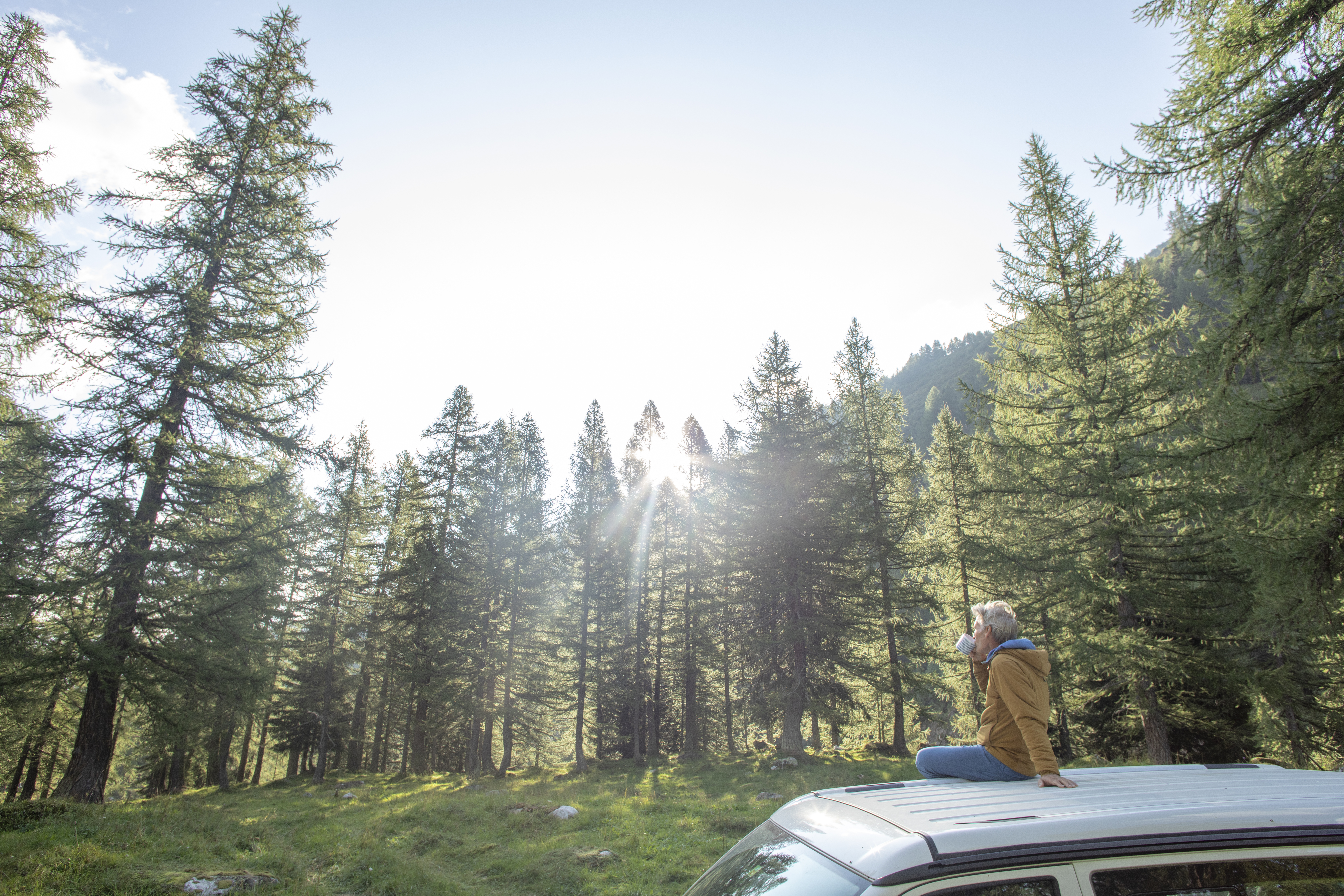 He enjoys a coffee and looks out towards lush forest surrounding 