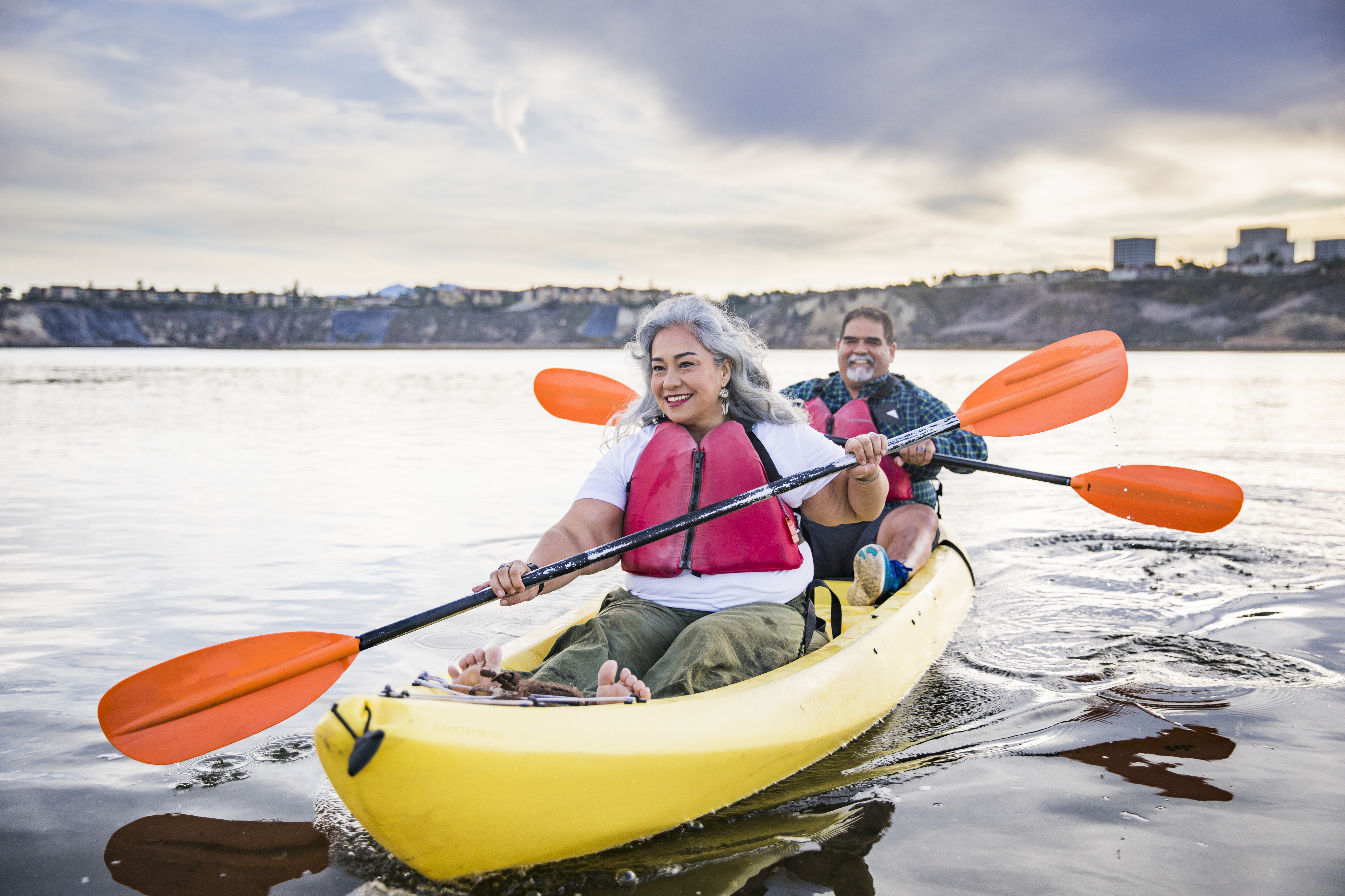 A couple kayaking on a flat river.