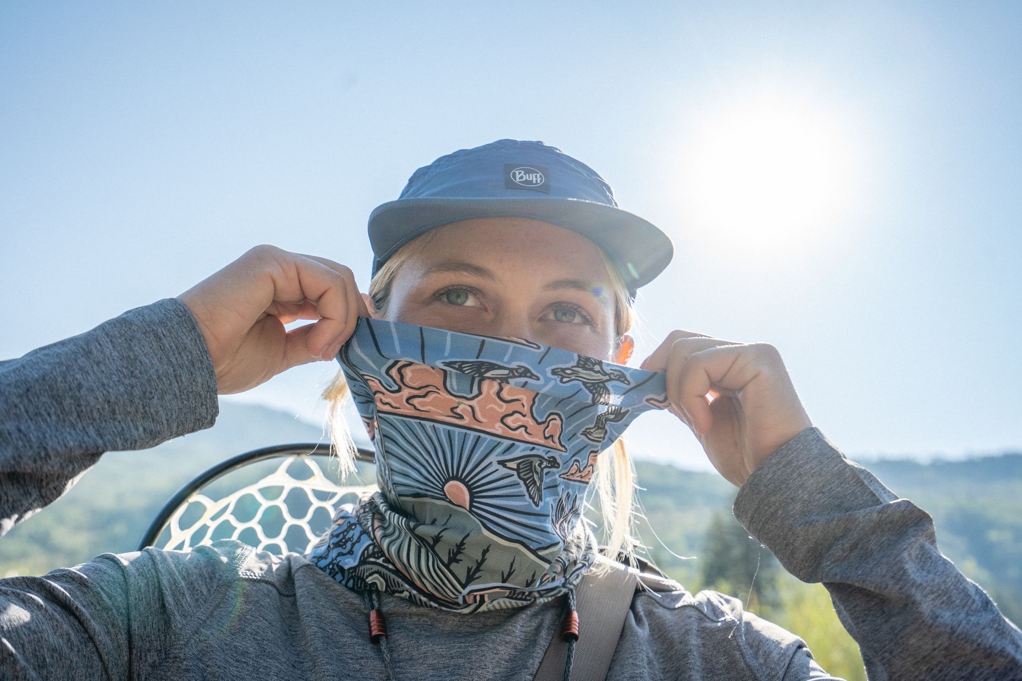 Person pulling a blue and orange buff above their face 