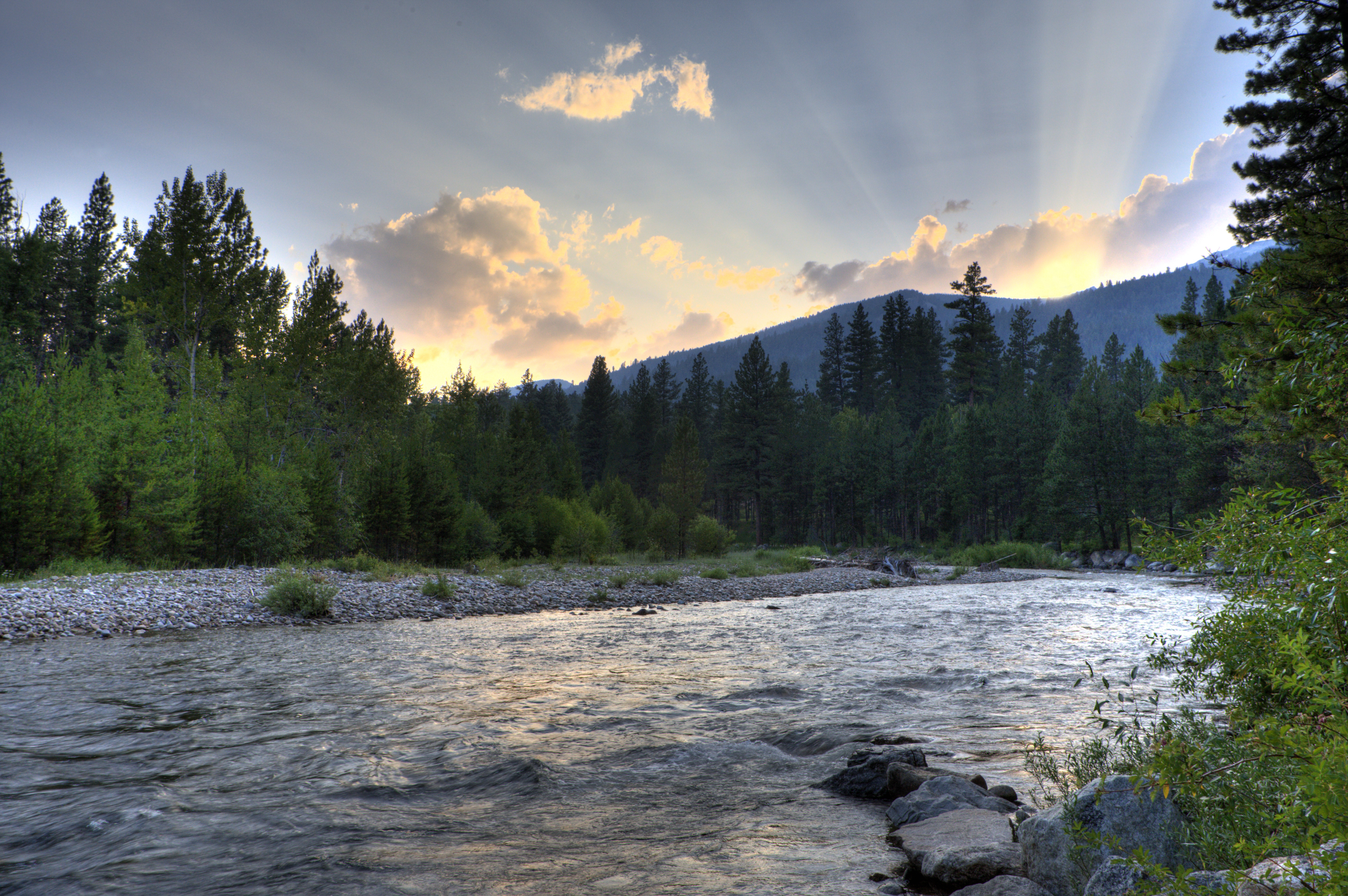 The rays of the setting sun illuminate the sky over the Bitteroot River. 