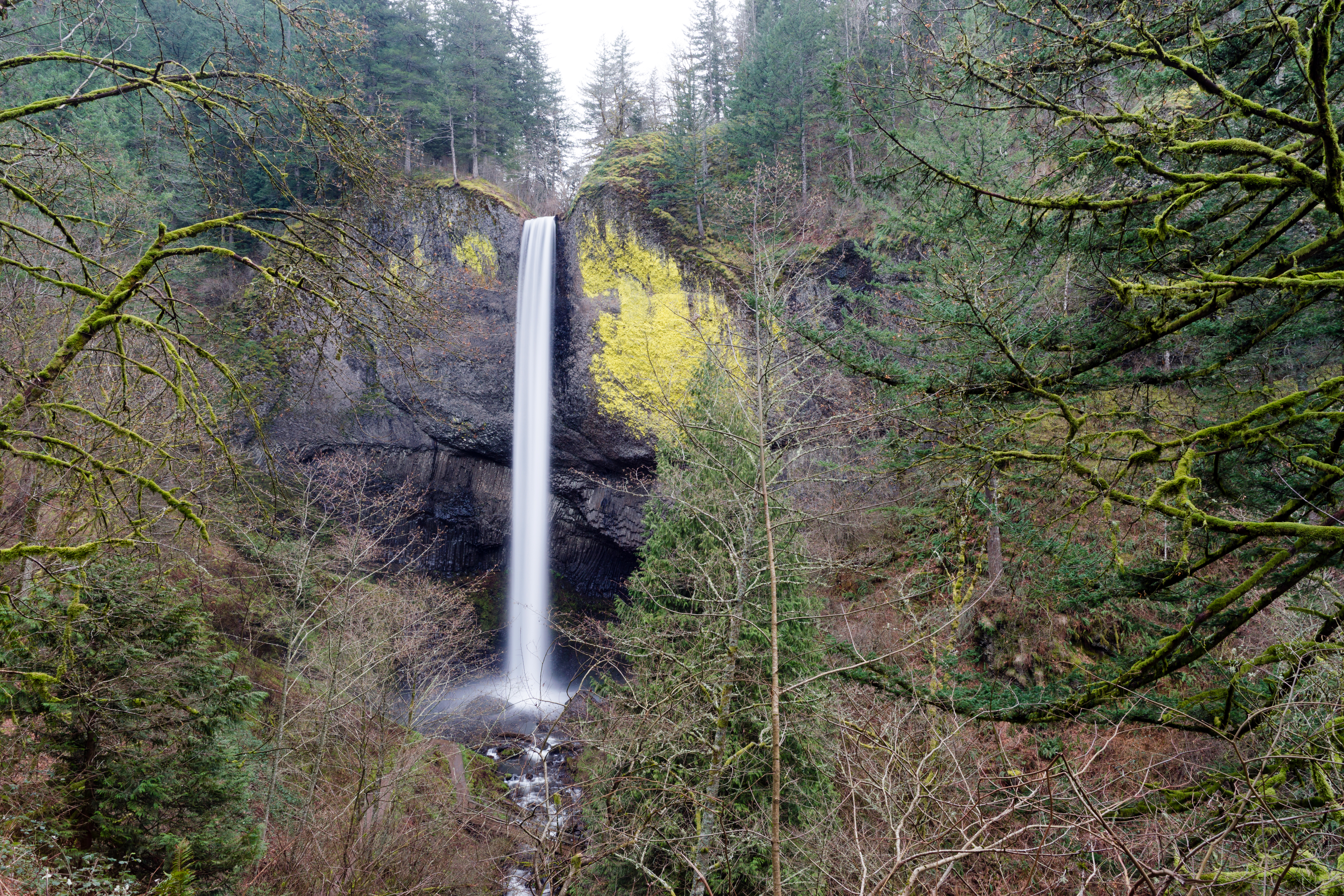 A solid beam flow of water from Mt Hood rushes down the cliff face