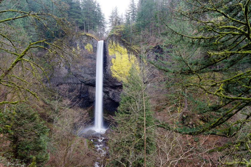 A solid beam flow of water from Mt Hood rushes down the cliff face