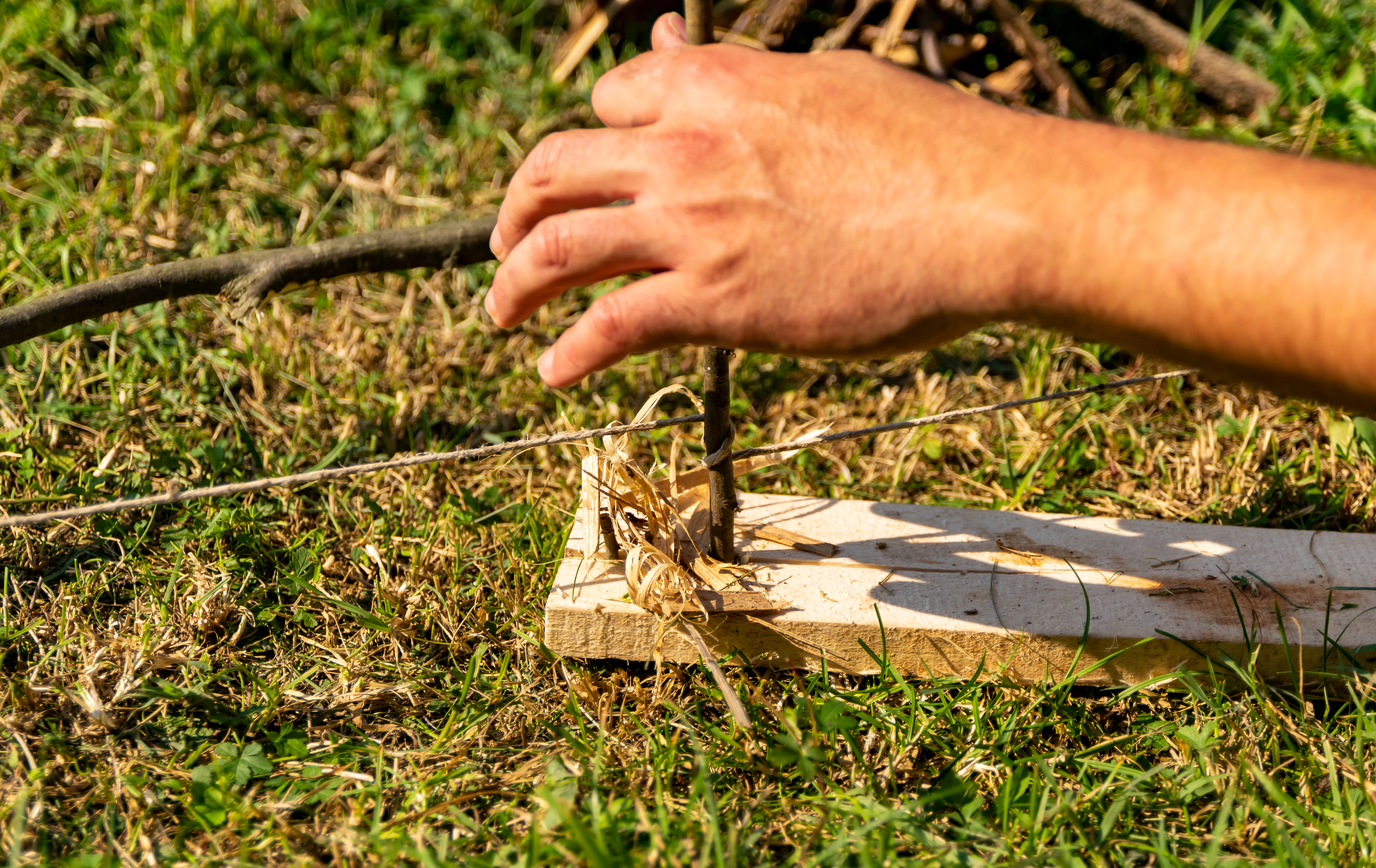 Hands using the bow drill method to start a fire.