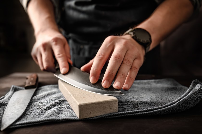 Man sharpening knifes with special stone tool, closeup view