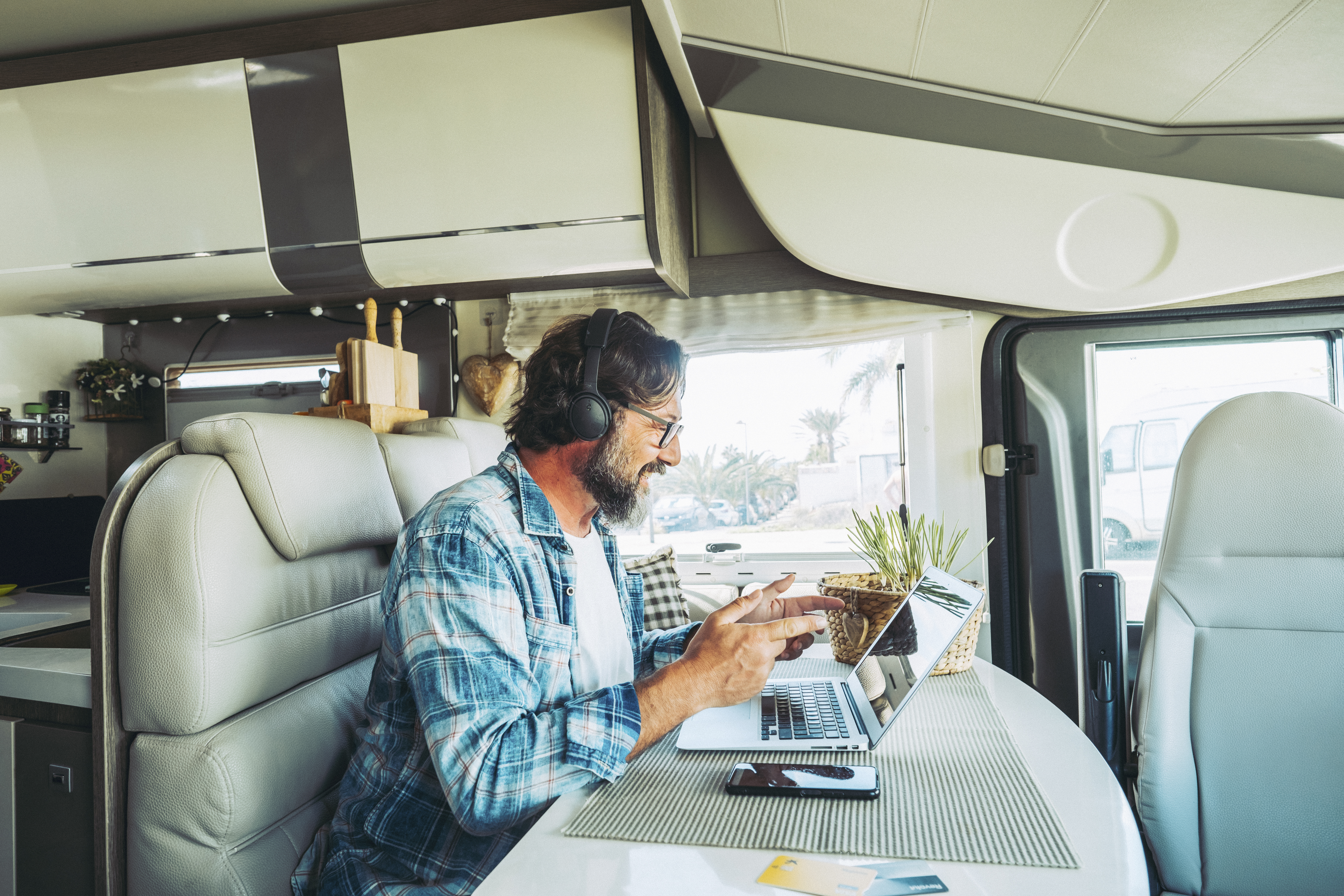 Working and traveling inside motor home camper van concept lifestyle people. One man using laptop to video call remote friends sitting on a table in camping car vehicle. Digital nomad office new