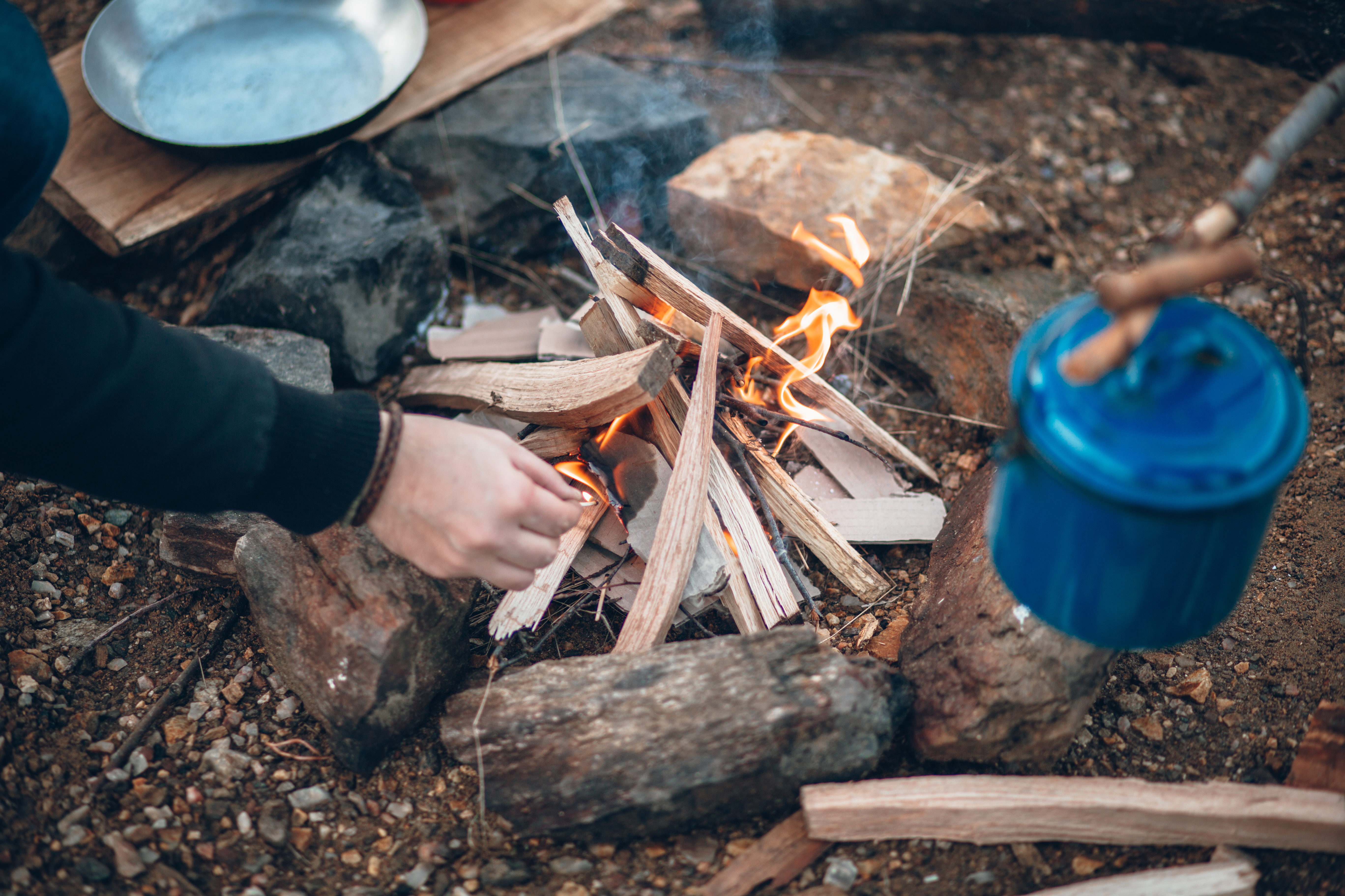 Young camper warming hands near campfire