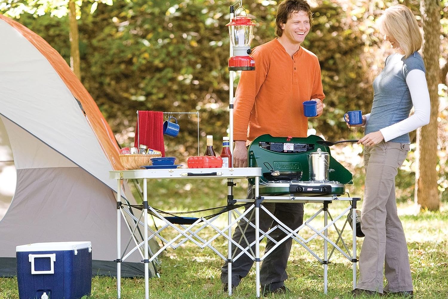 Coleman Pack-Away camp kitchen at a campsite with two people.