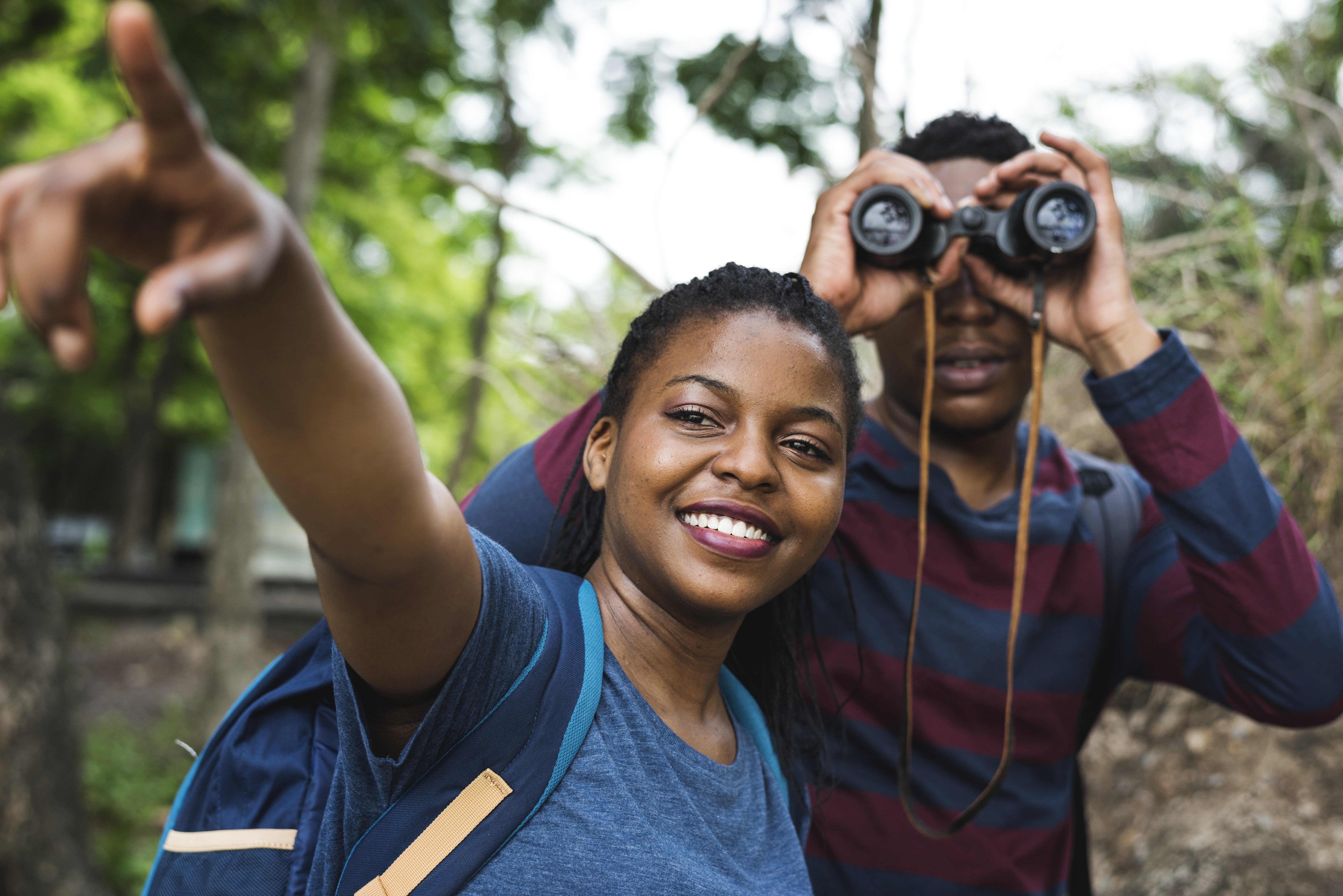 Couple sight seeing with binoculars in the forest