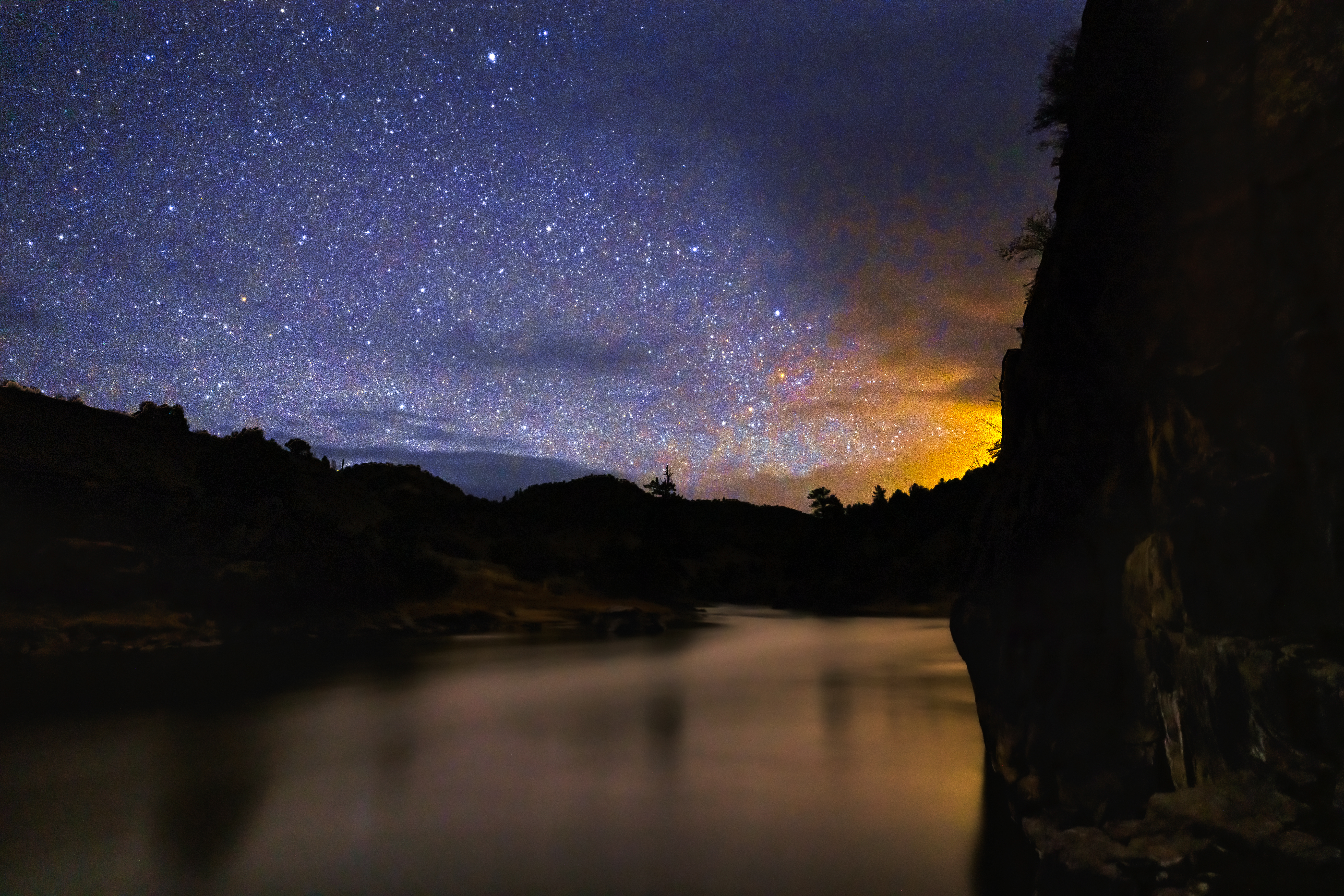 Starry Dark Night Along Scenic River - Flowing river at night with dark sky full of stars. Scenic night photography astro landscape.