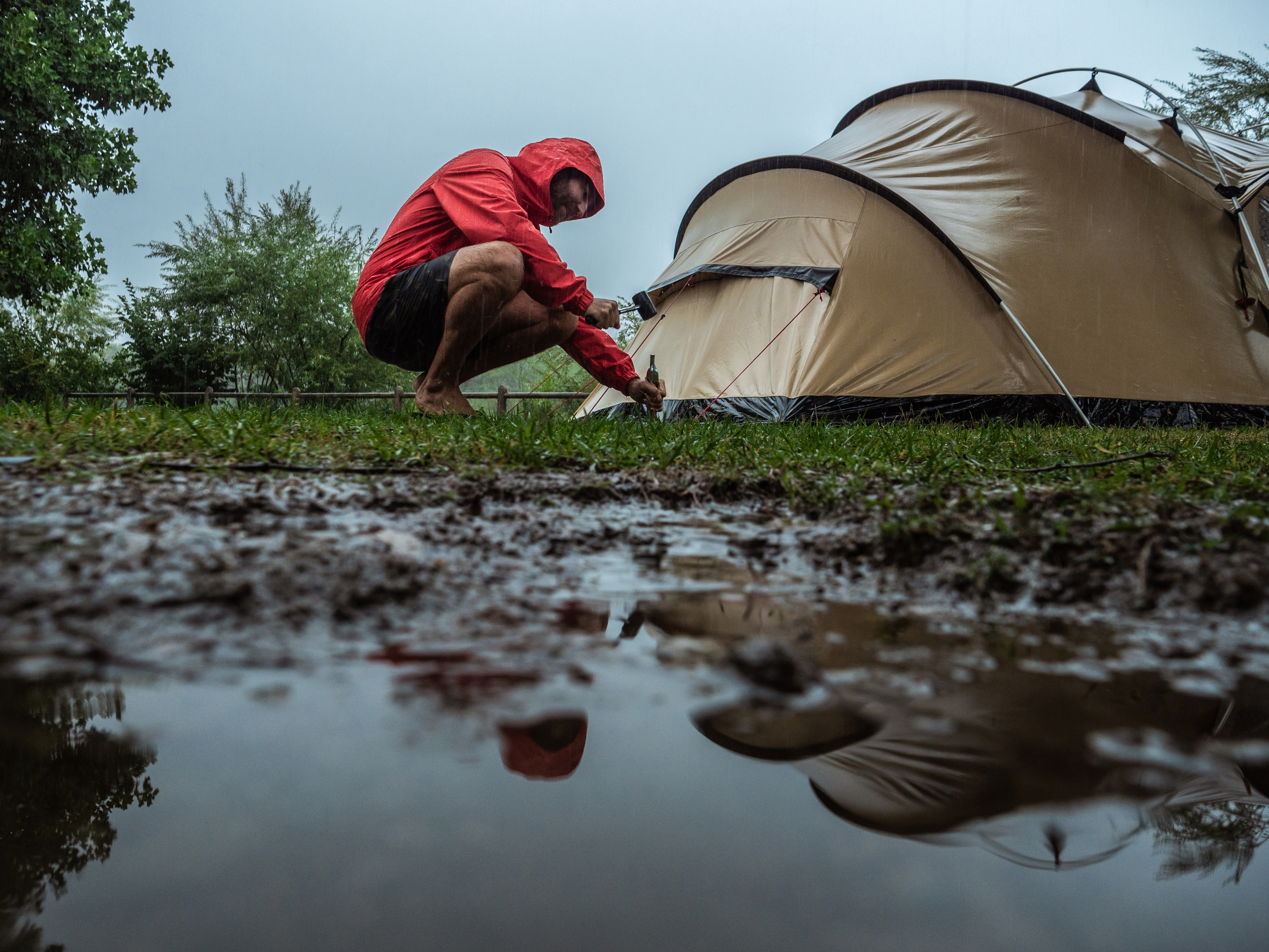 Man camping fixing tent on rainy day