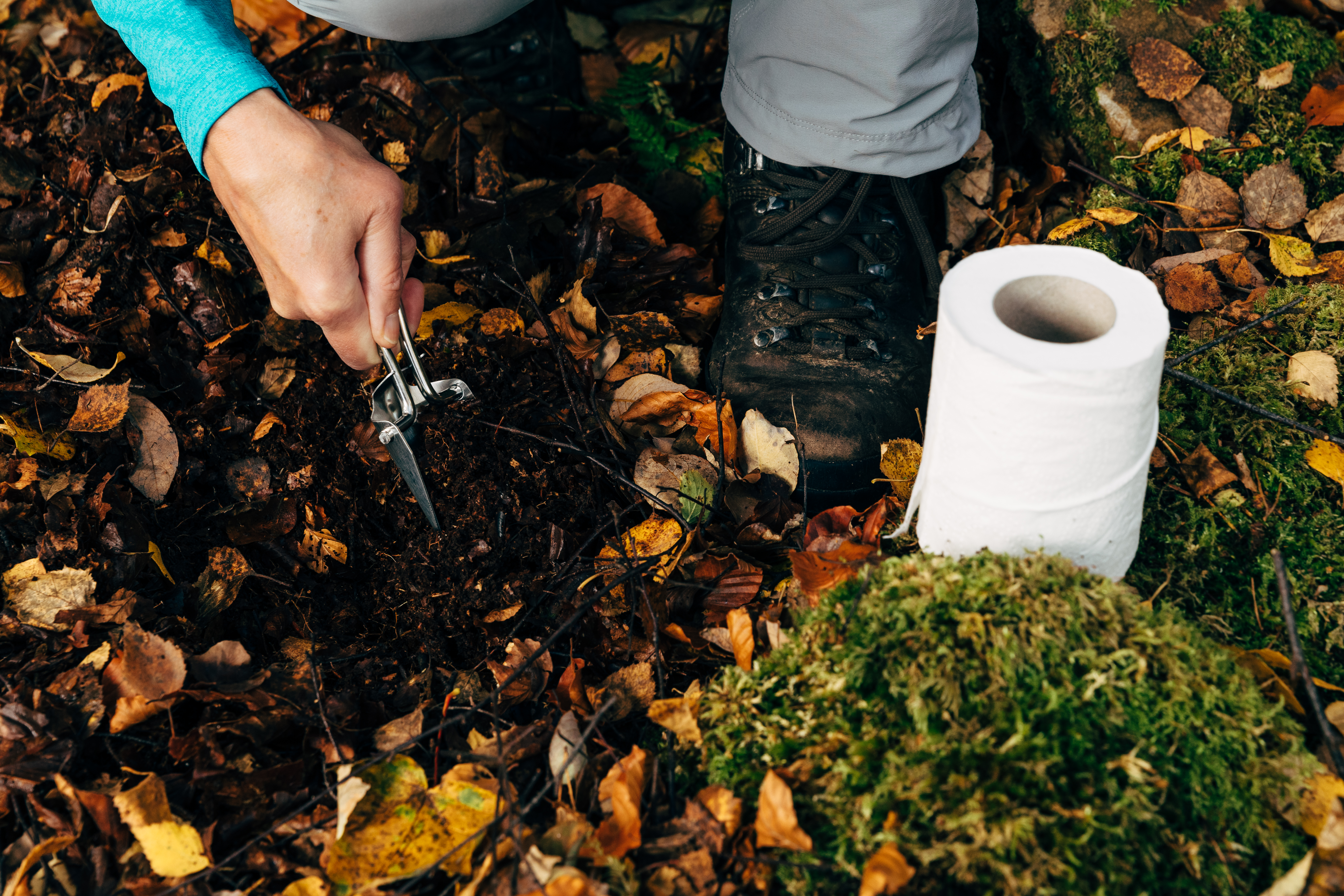 Part of a series showing a female hiker preparing an outdoor toilet stop in the woods.