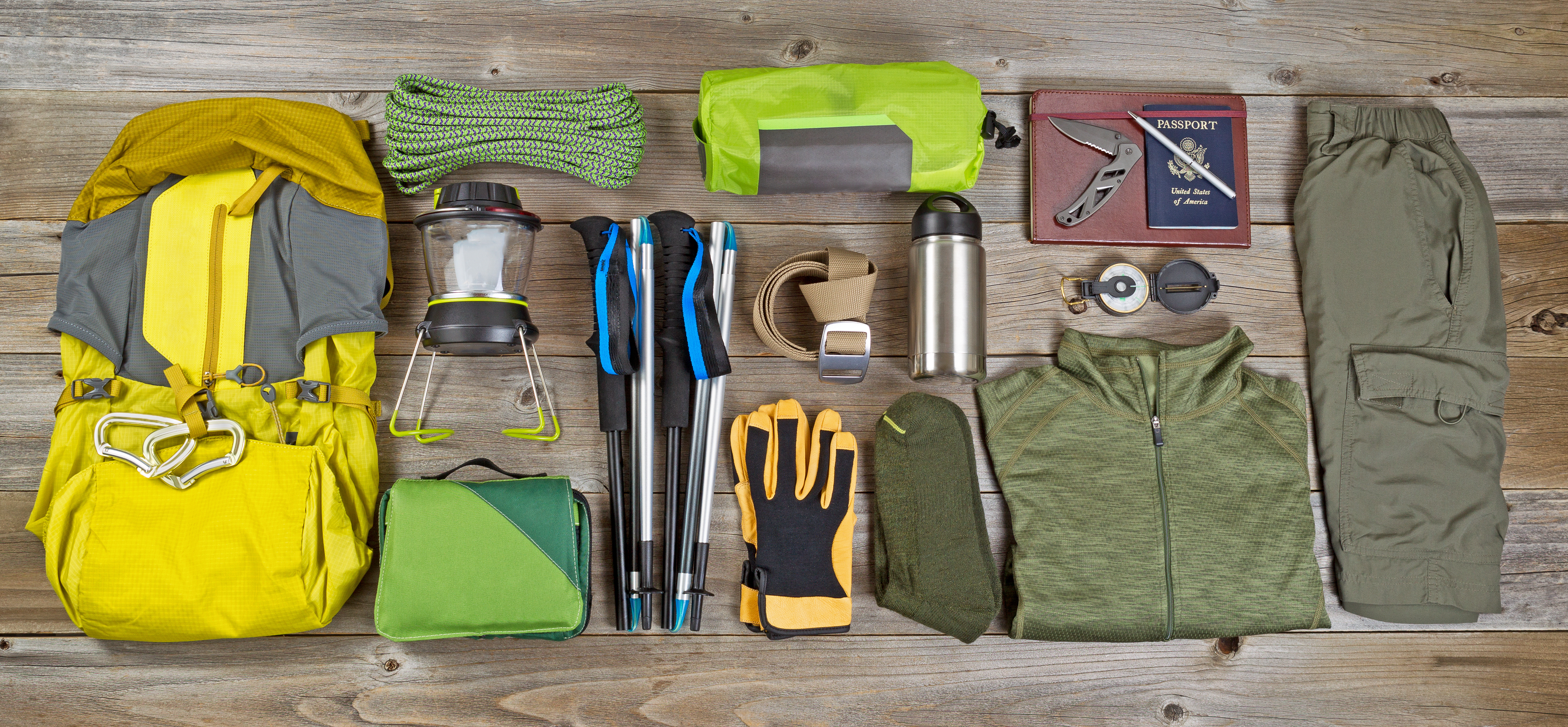 High angled view of organized hiking gear placed on rustic wooden boards in rectangle format.