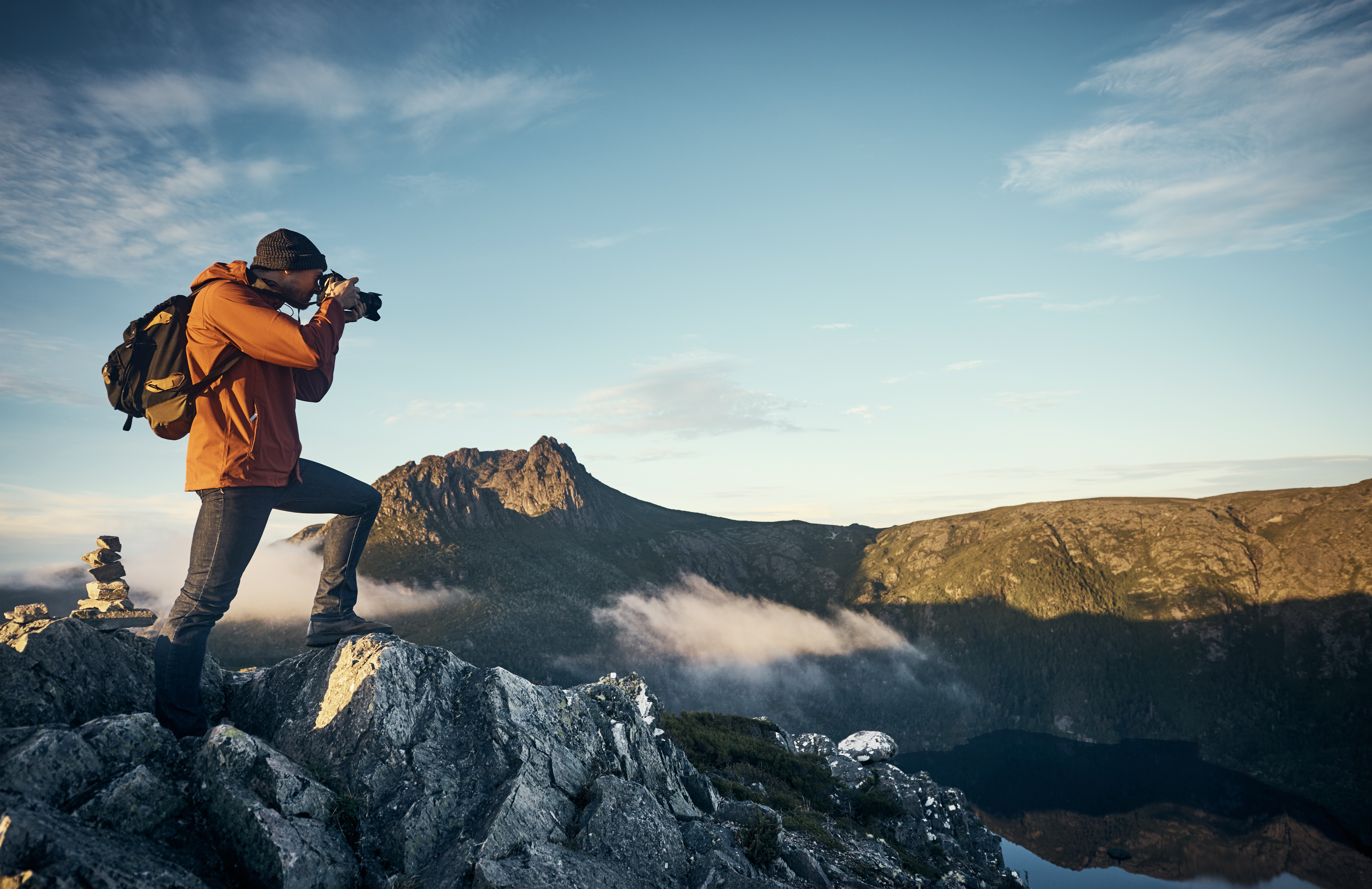 A young man taking photographs while hiking in the mountains.