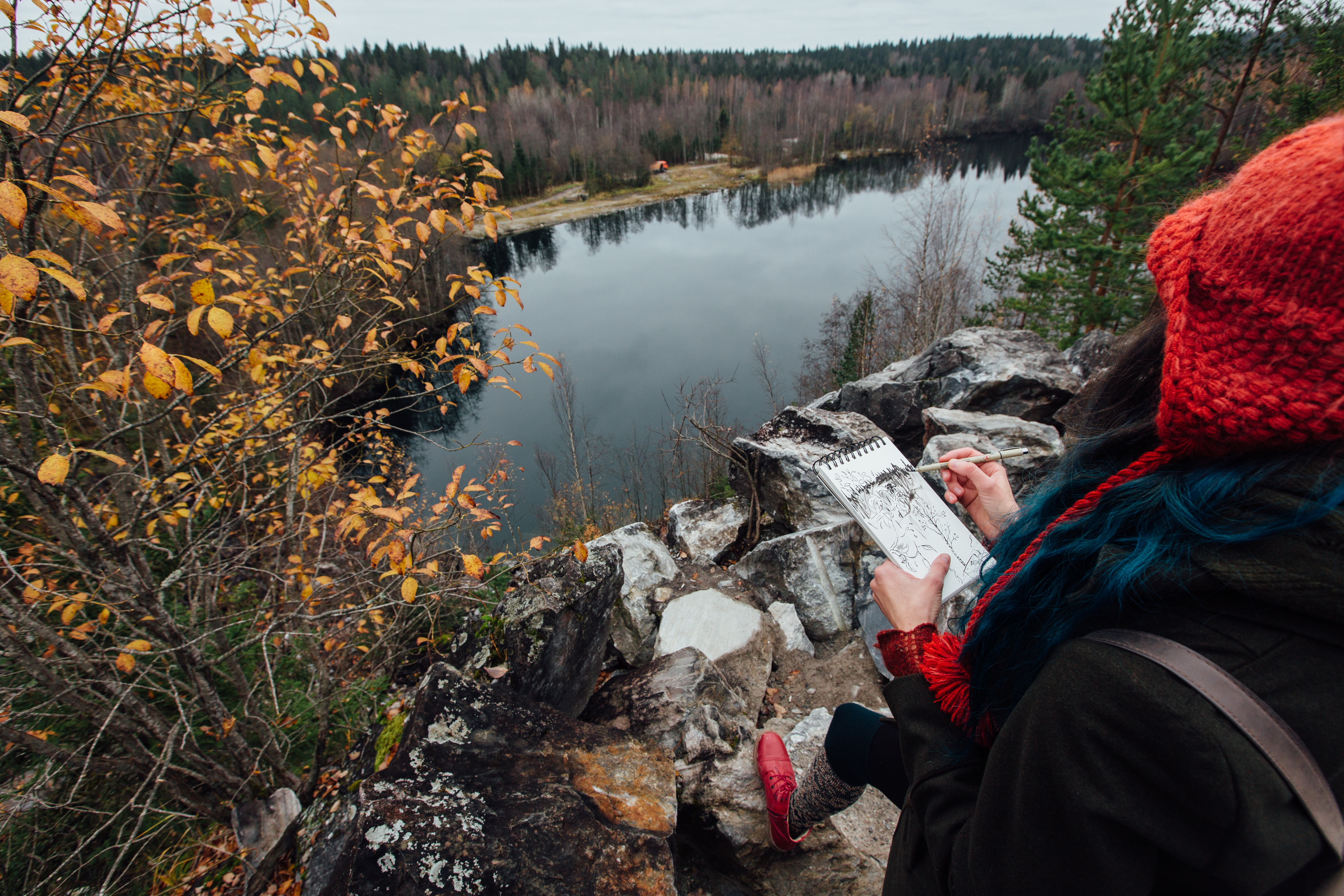 Artist painting while sitting on the rocks at the cliff.