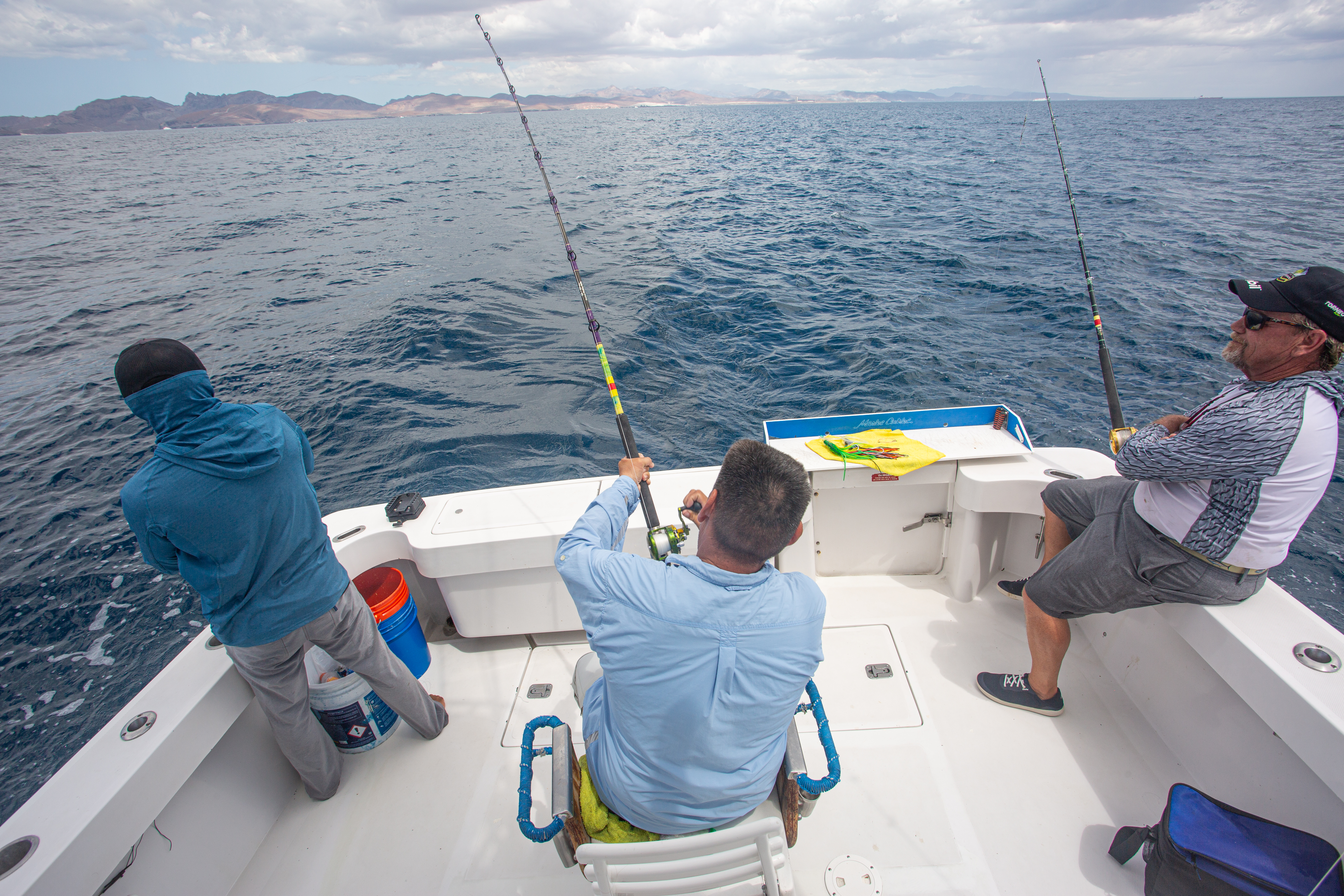 3 people fishing on a small white boat in the water