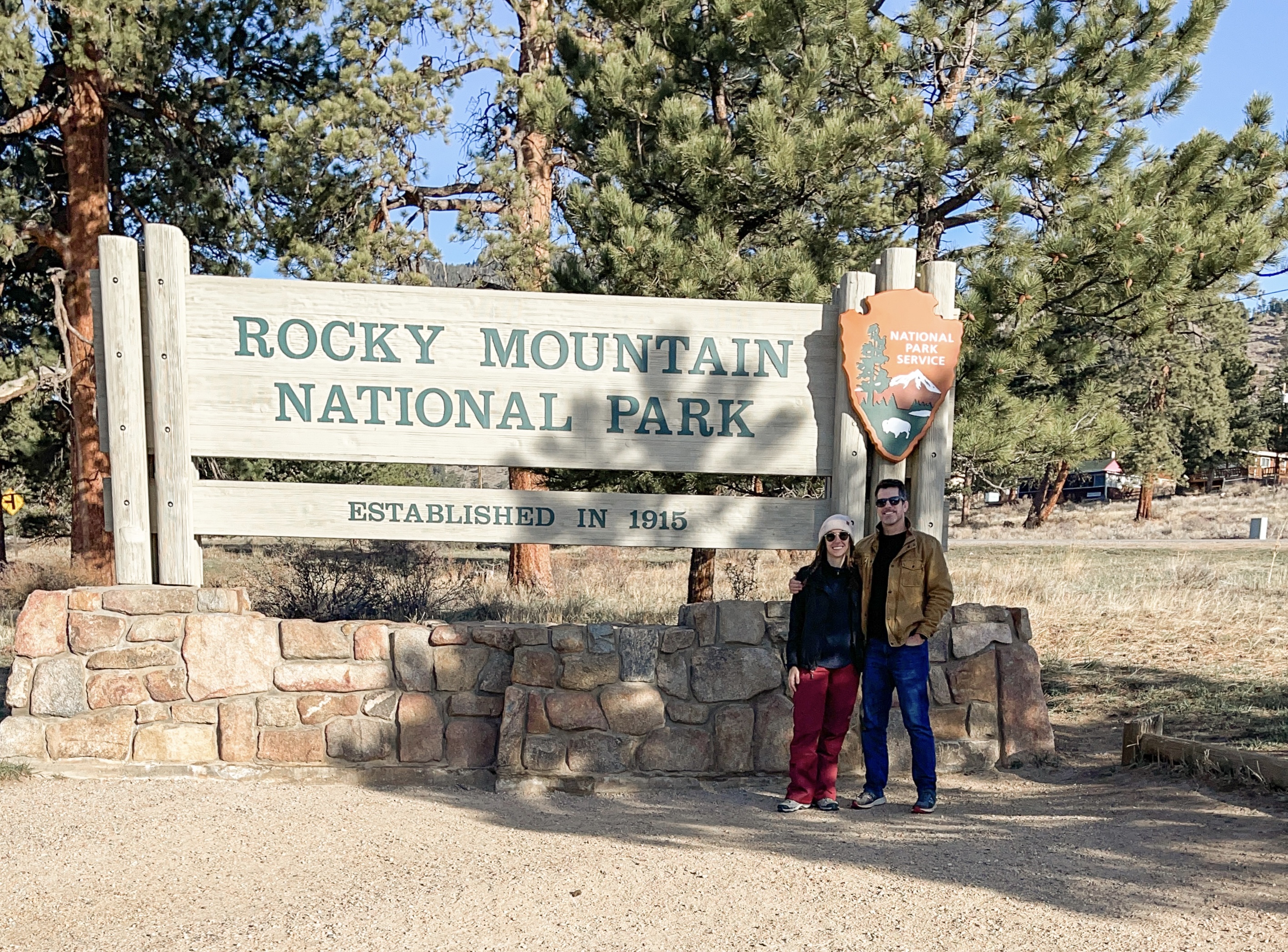 Author and companion standing in front of Rocky Mountain National Park sign 