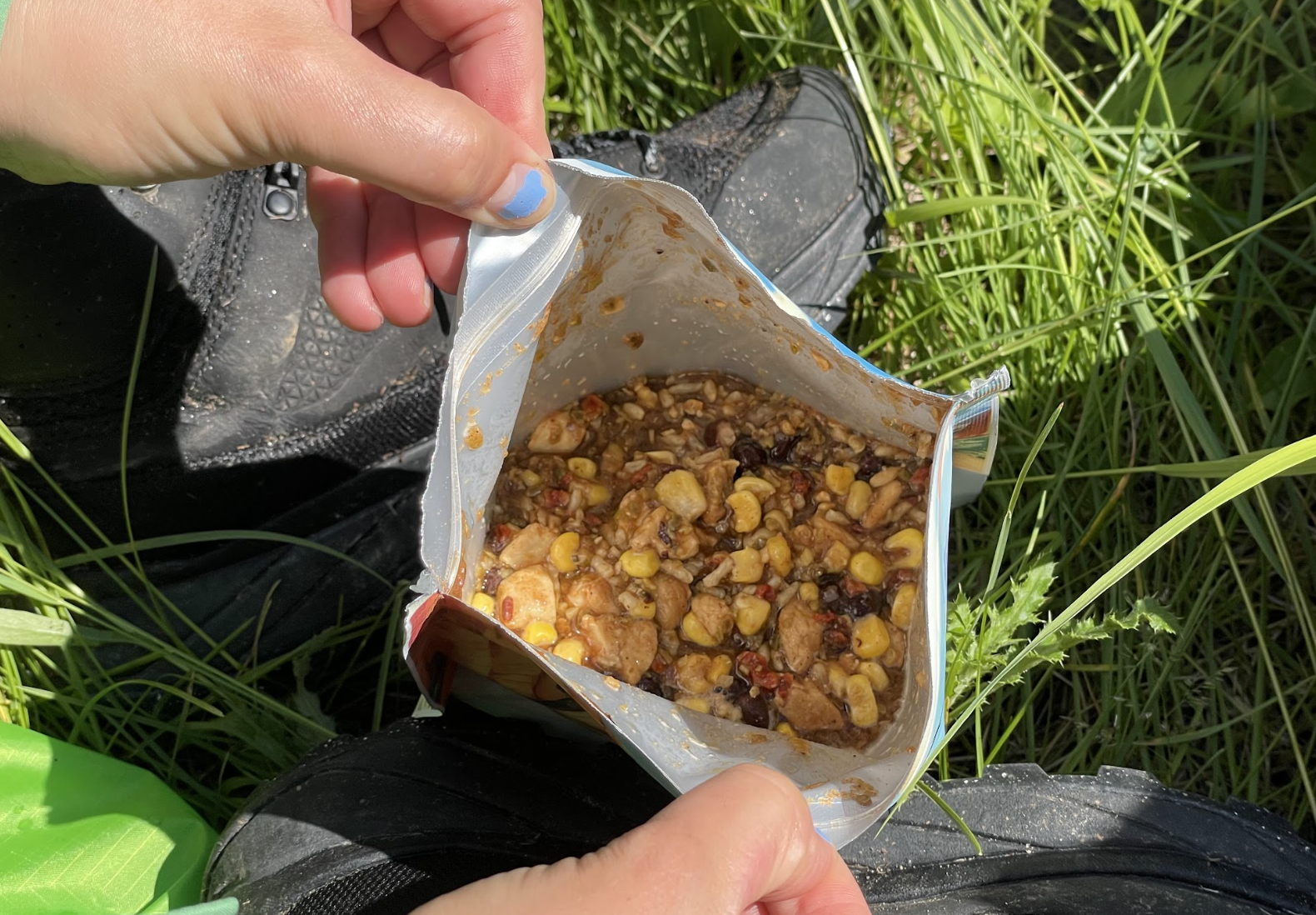 An opened package of Backpacker's Pantry Rice and Beans over a patch of grass