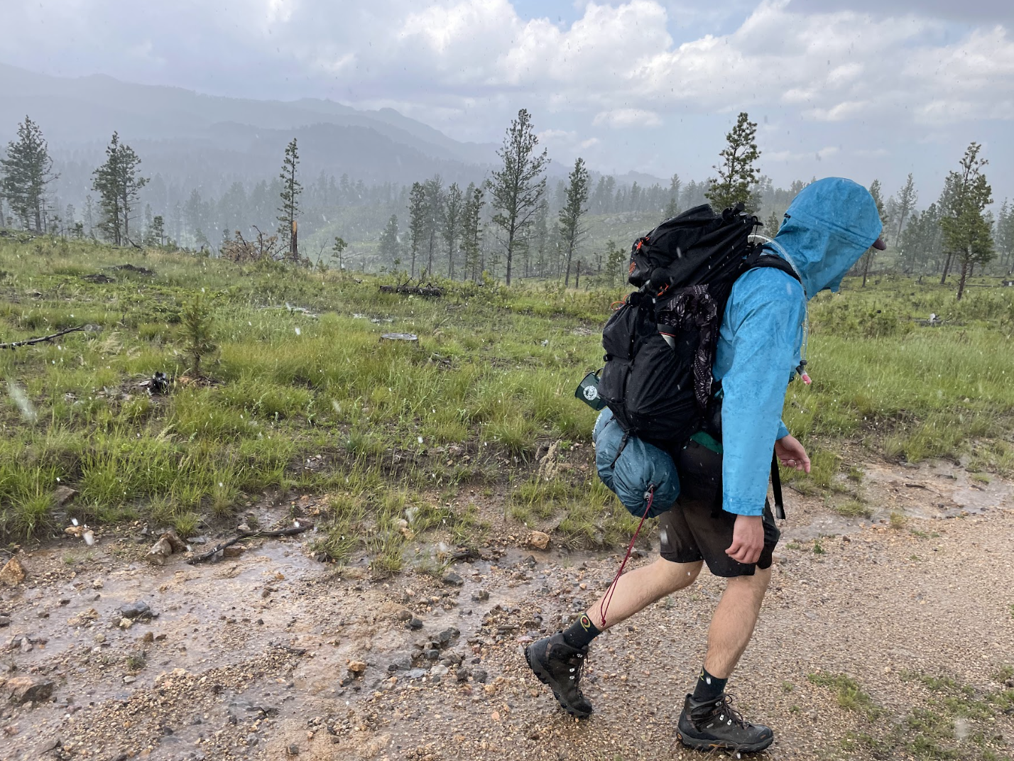 Person wearing a blue jacket and brown hiking boots walking down a trail