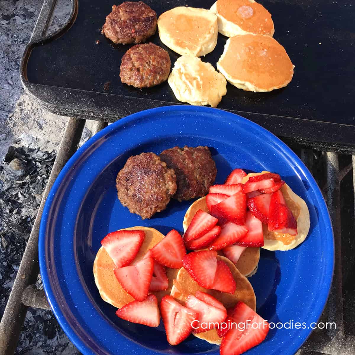 Pancakes with strawberries spread over them on a blue plate