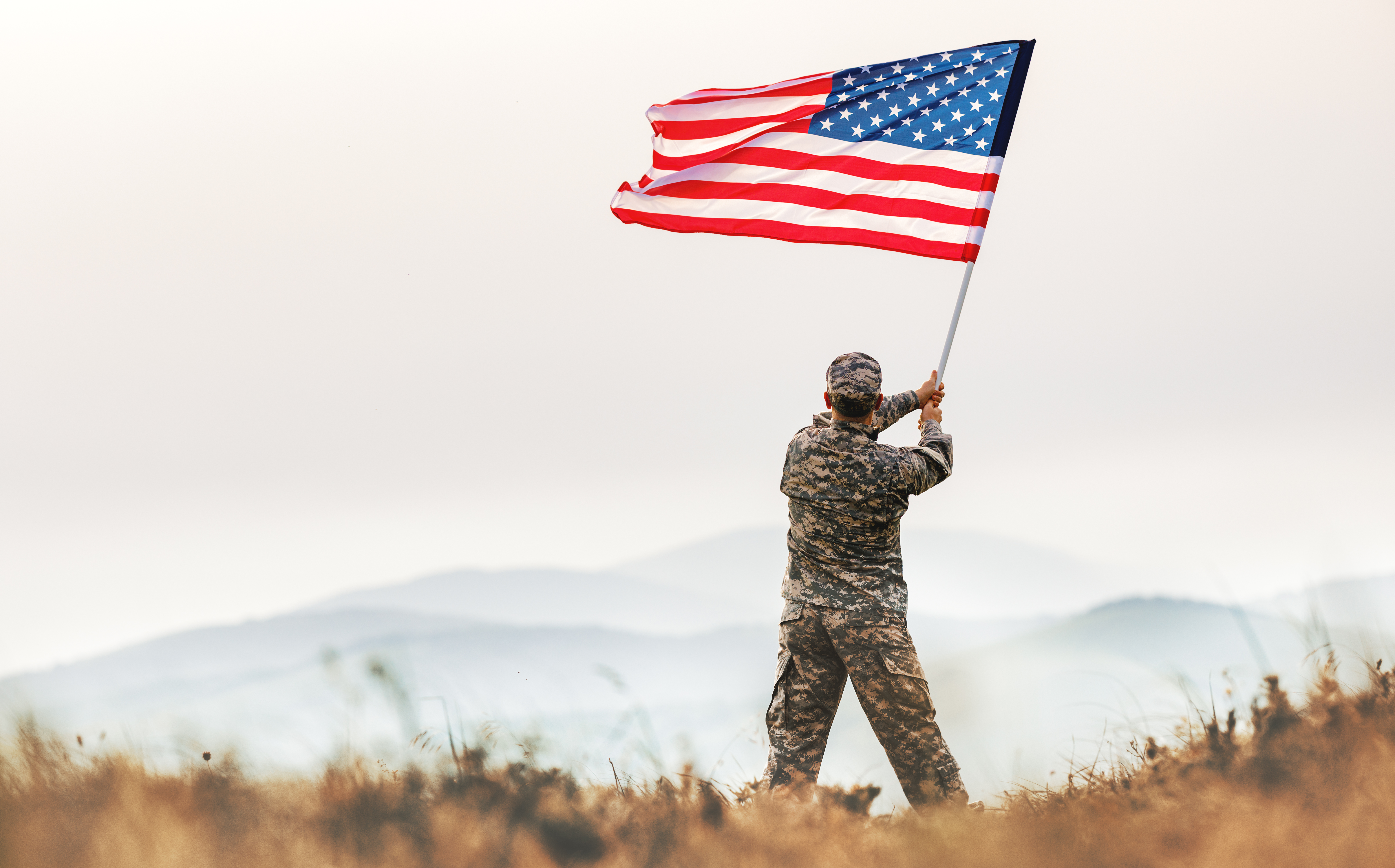 A veteran waving an American flag in the outdoors.