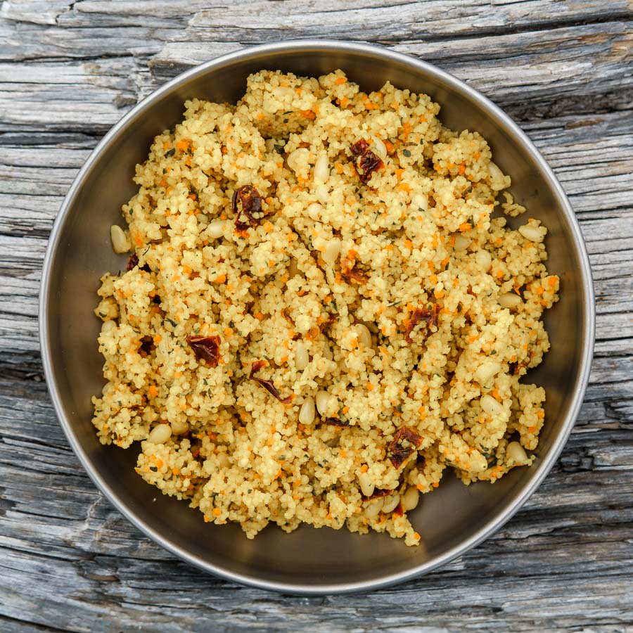 Sun dried tomato couscous in a silver bowl on top of a wooden table