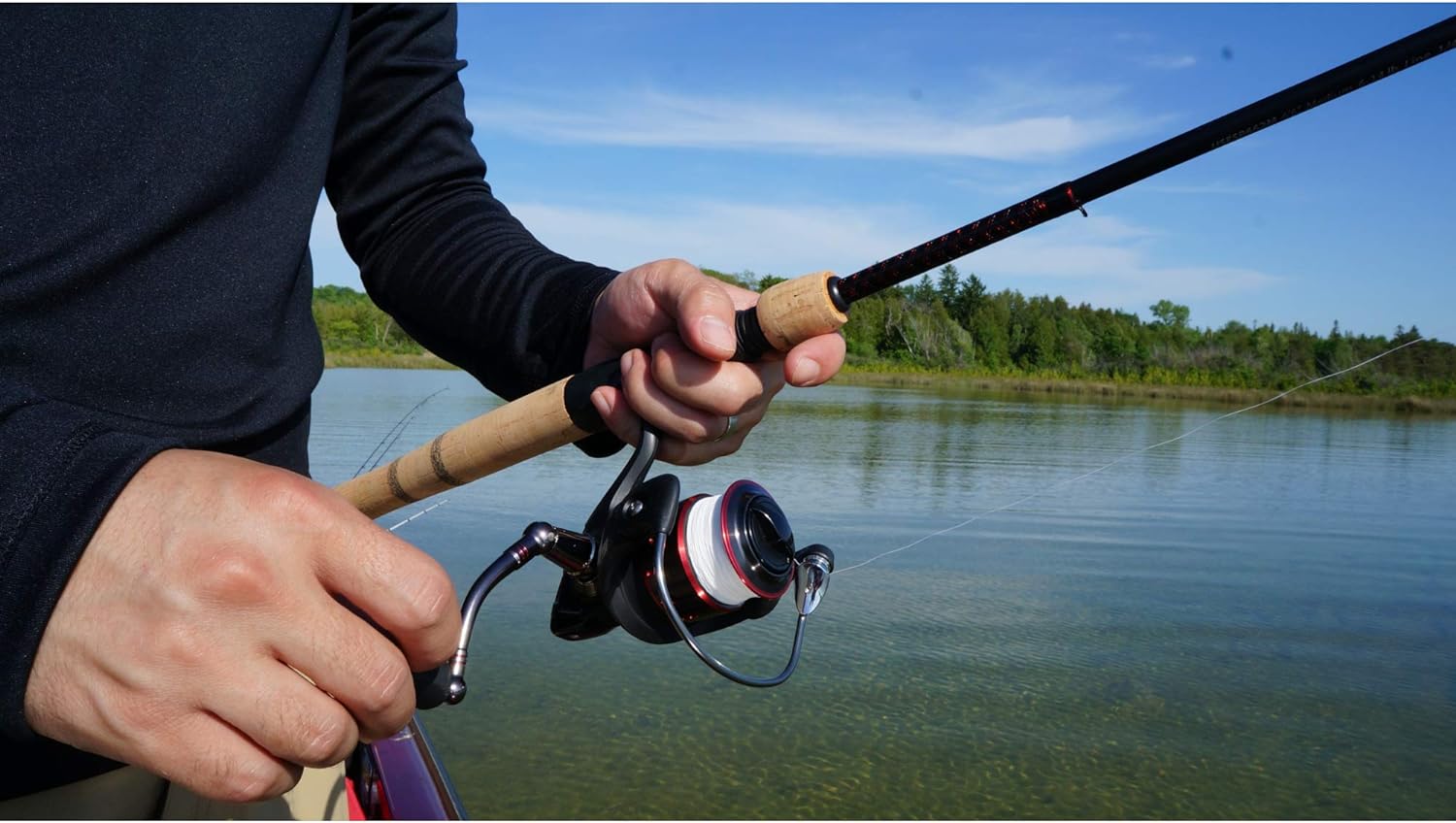 A person holding a black and wooden Ugly Stik Fishing Rod