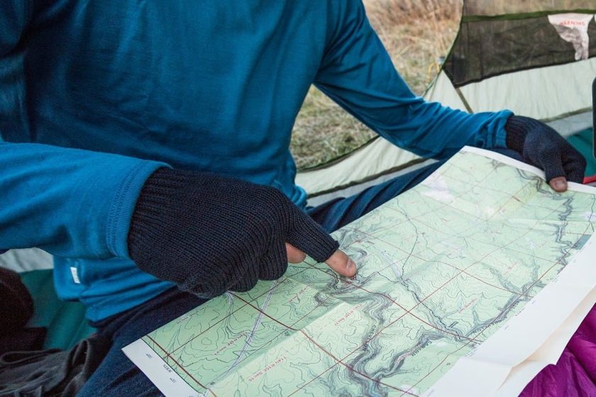 Person using black fingerless gloves while pointing at a map