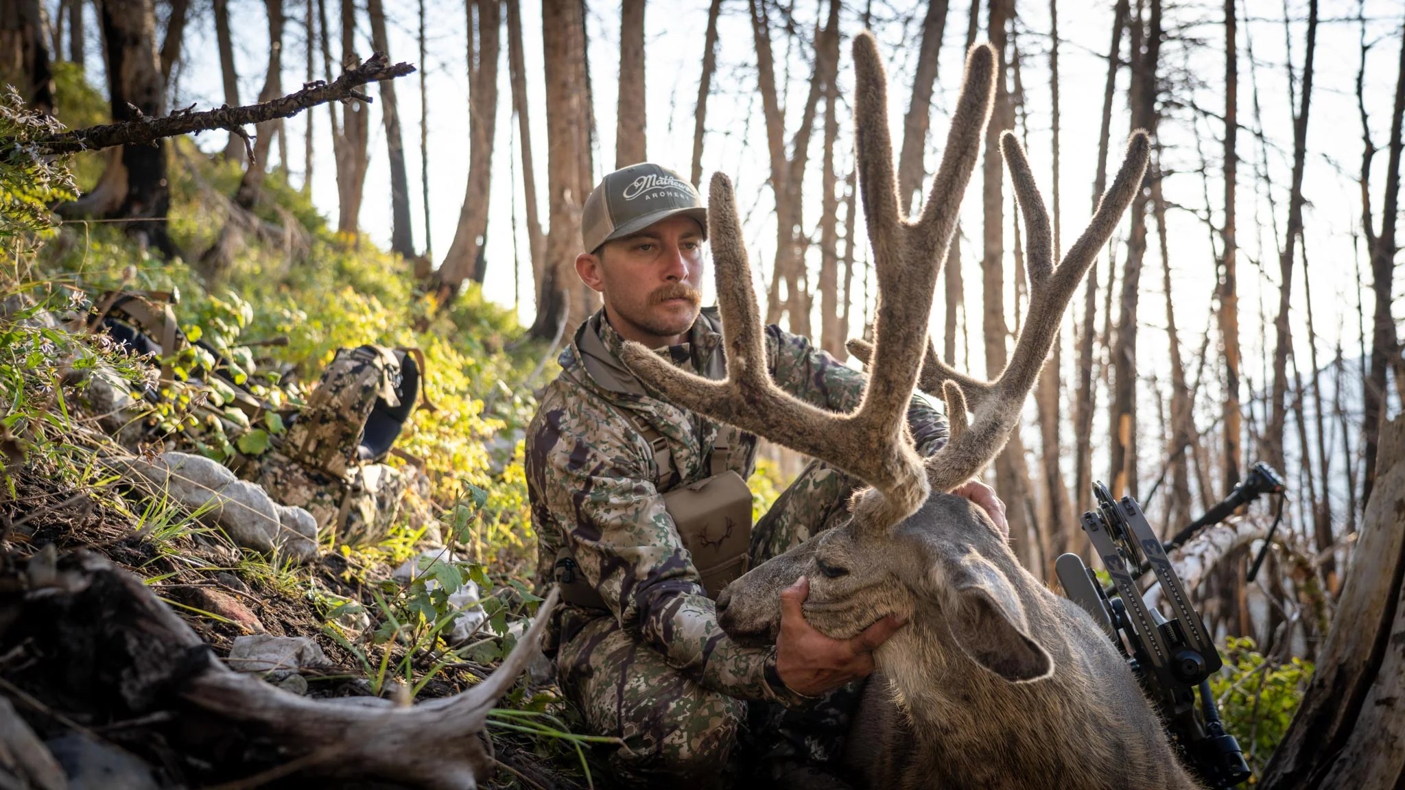A hunter wearing Kryptec apparel while holding a deer
