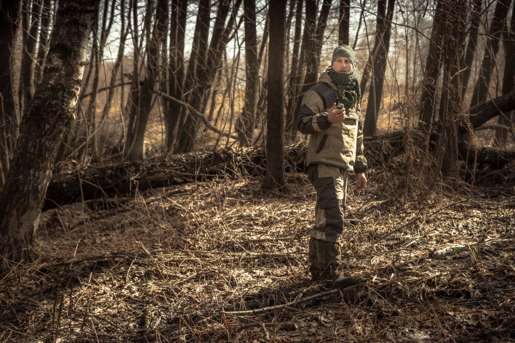 Hunter man autumn standing in forest with transmitter during hunting season