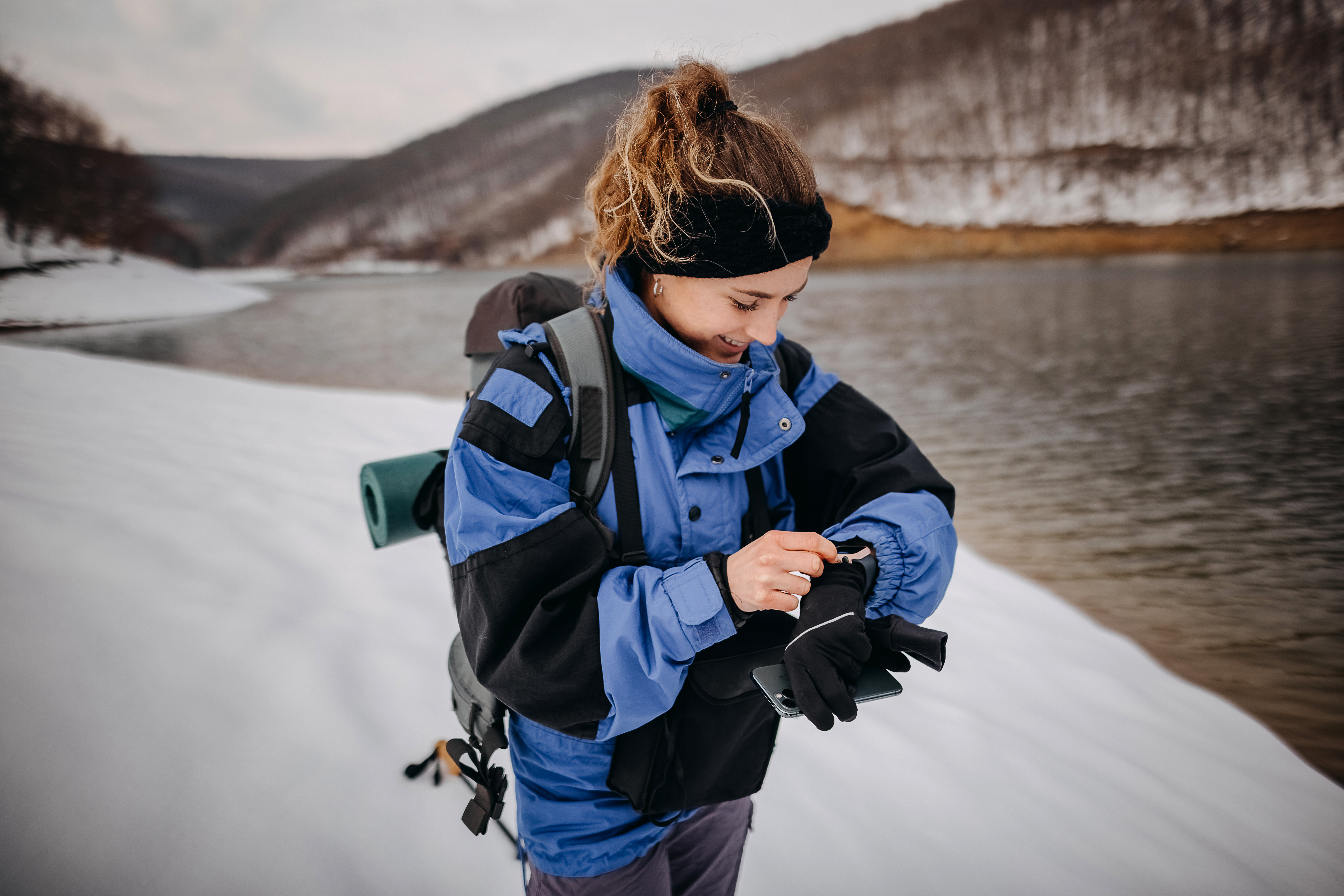 Woman hiker checking sports watch in winter woods and mountains