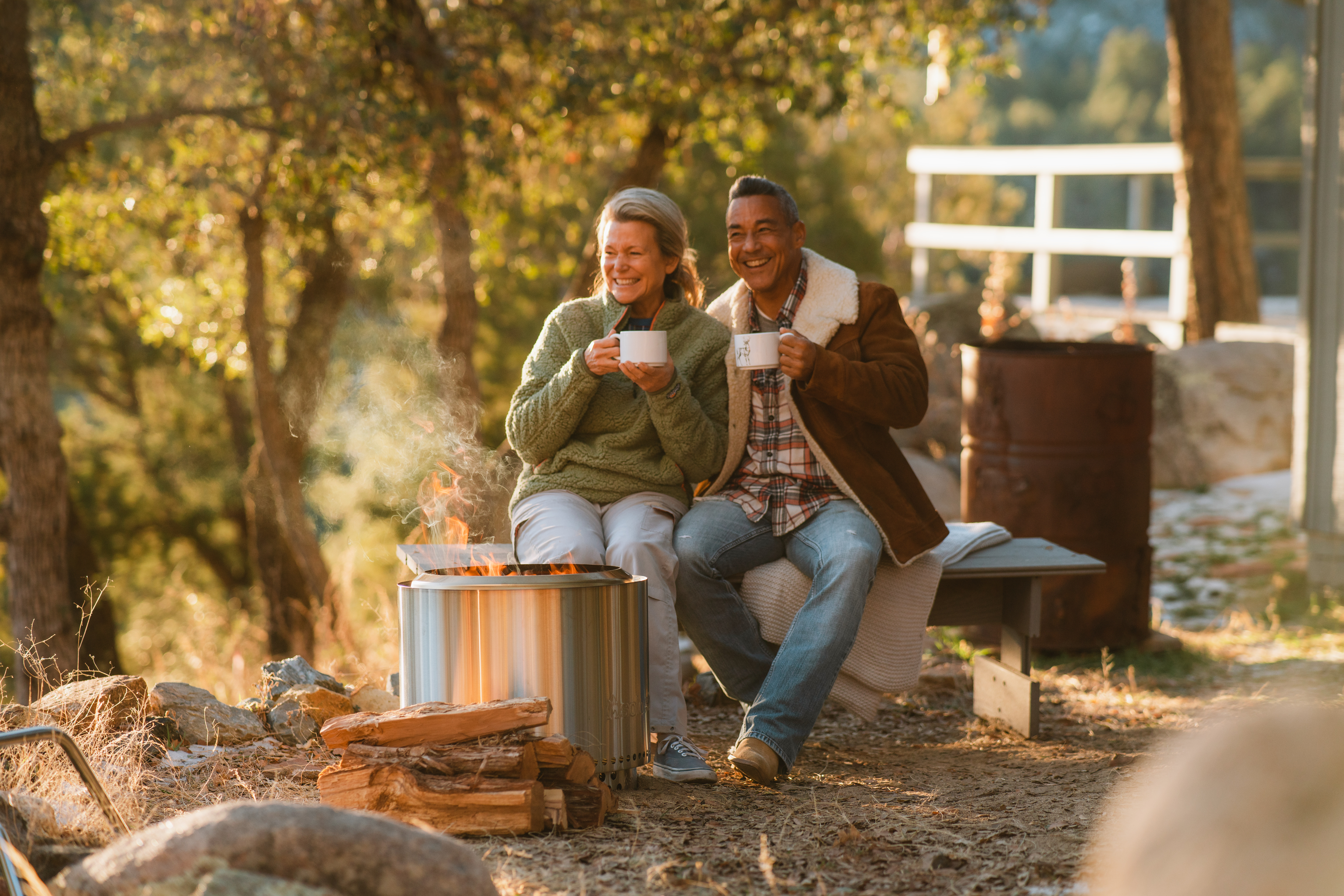 Two people sitting and drinking coffee in front of a solo stove