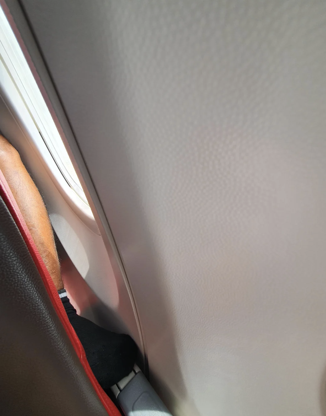 Photo of a person shoving their foot through the arm rest of a plane 